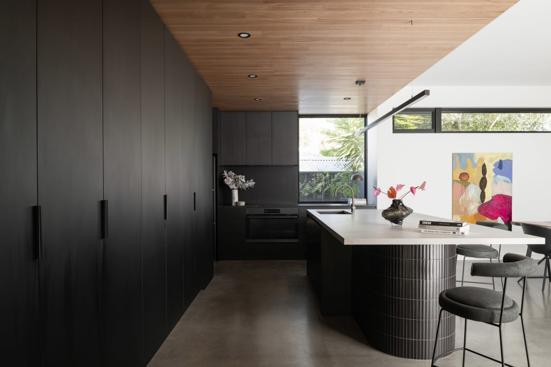 An elegant modern kitchen featuring black stainless steel appliances and concrete countertops.