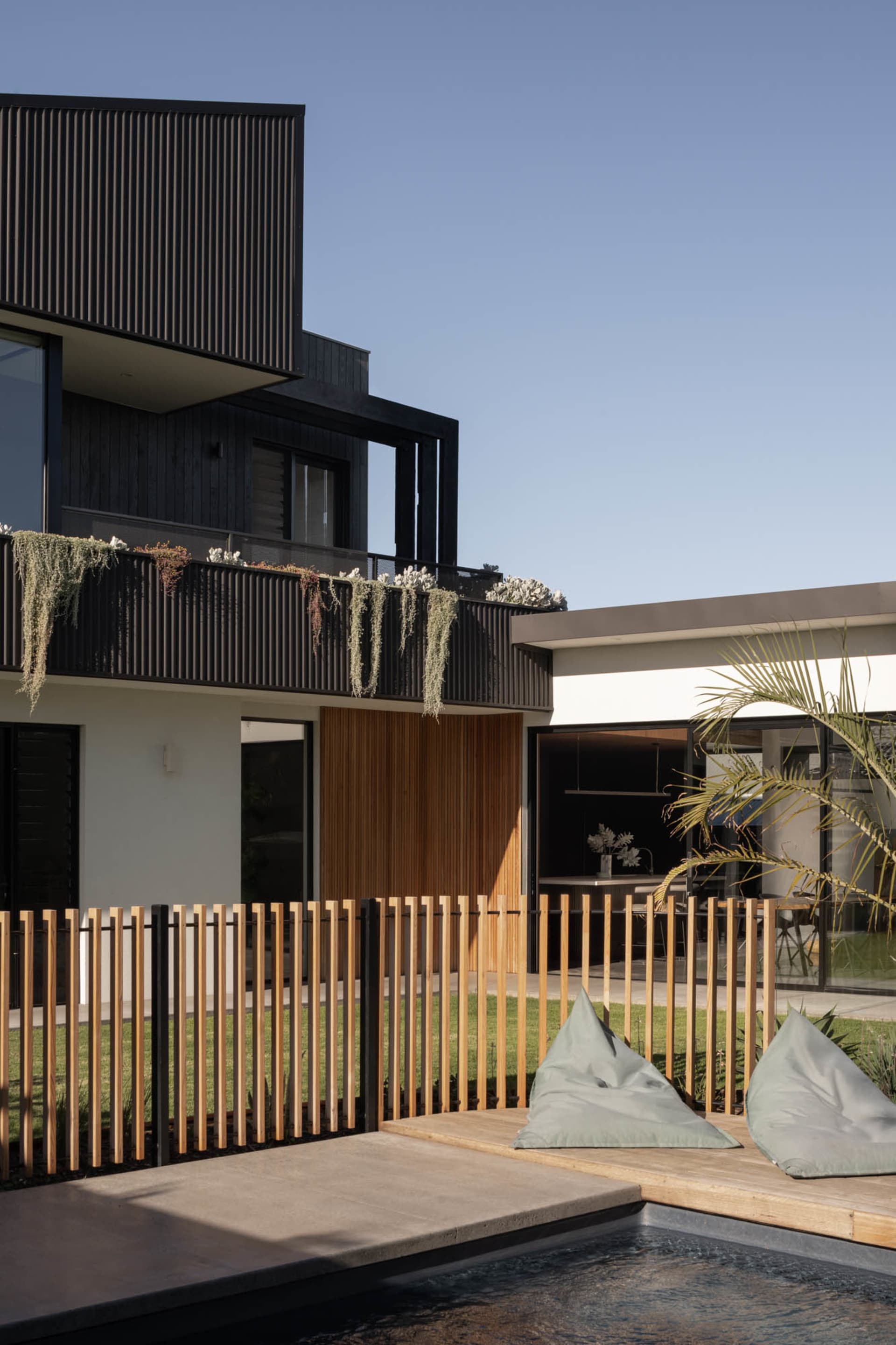 Modern residential exterior featuring black steel panels and wooden accents.