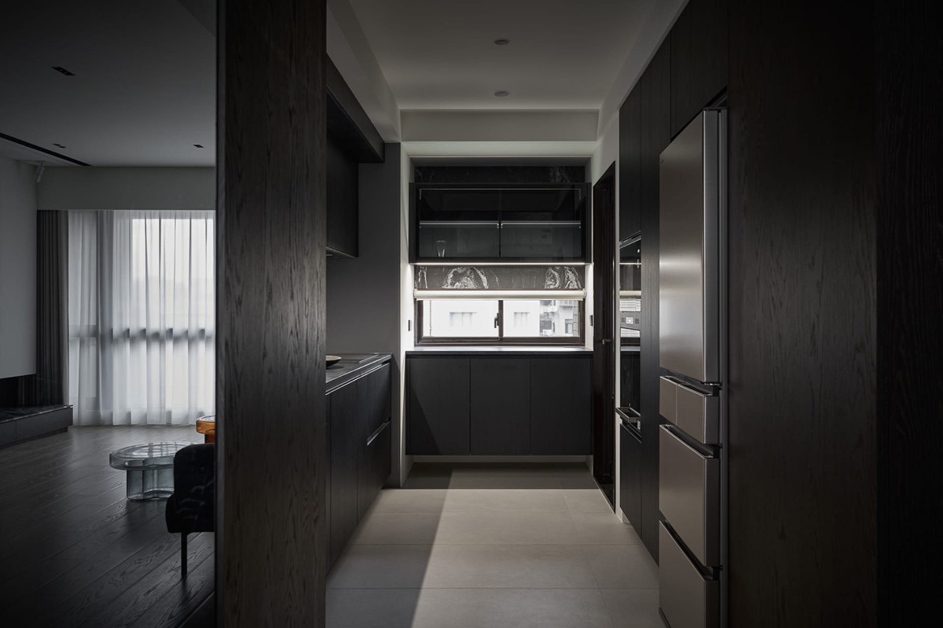 Modern kitchen with black cabinets, wooden floor, and stainless steel appliances.