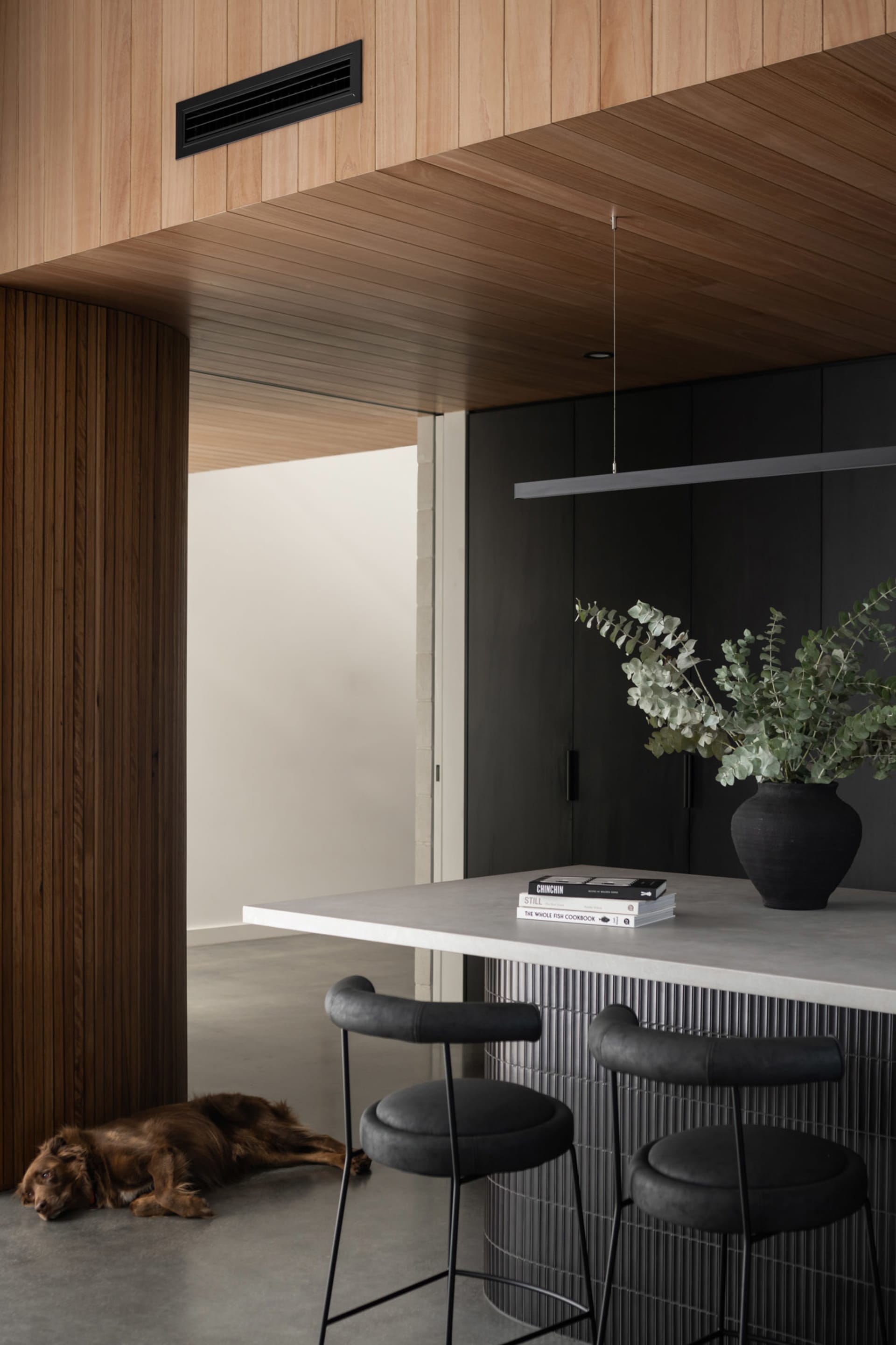 Modern kitchen interior featuring a concrete countertop, wooden cabinets, and a metal faucet.
