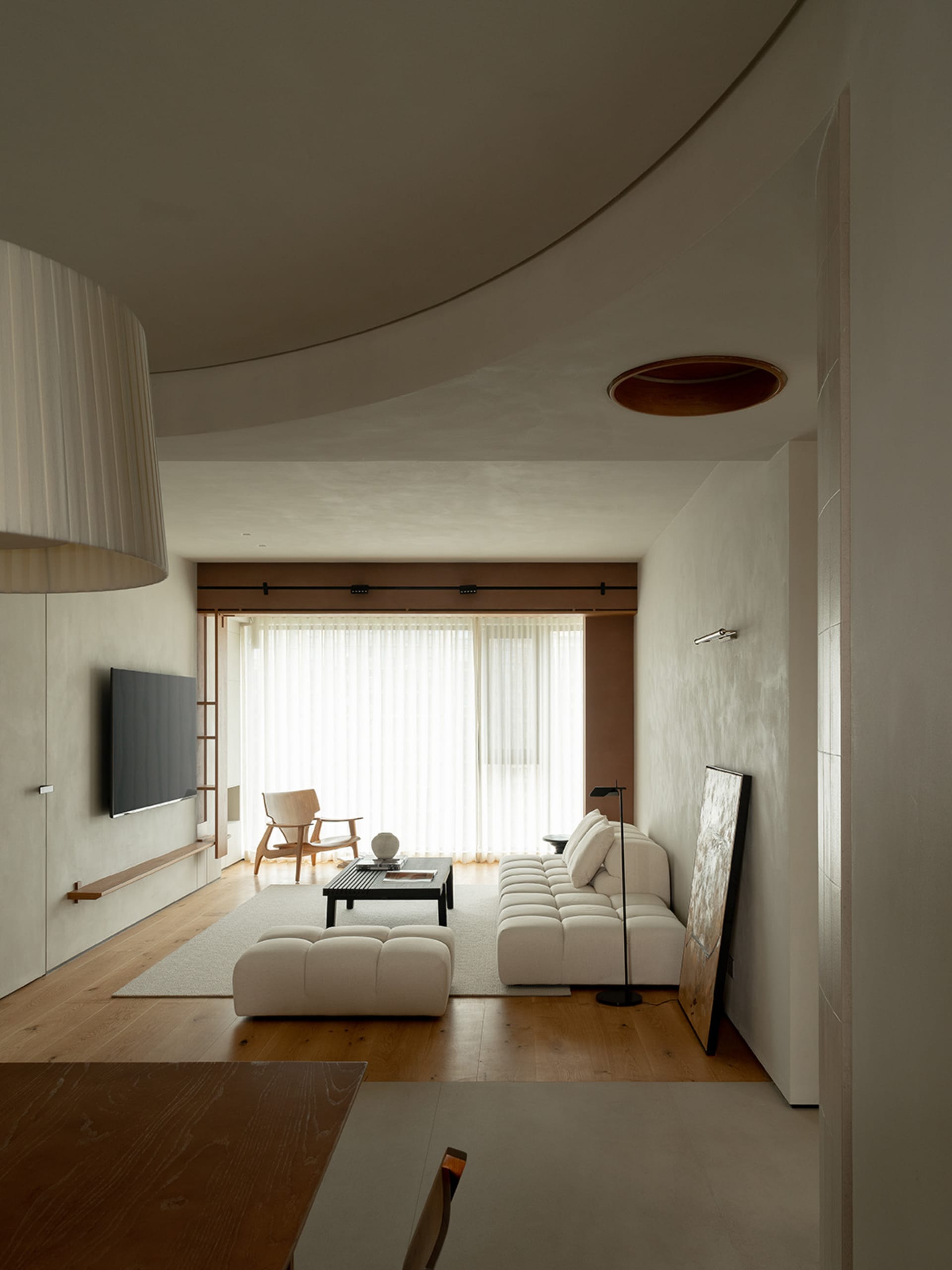 A modern living room featuring neutral-toned furniture and materials, with a minimalist design aesthetic.
