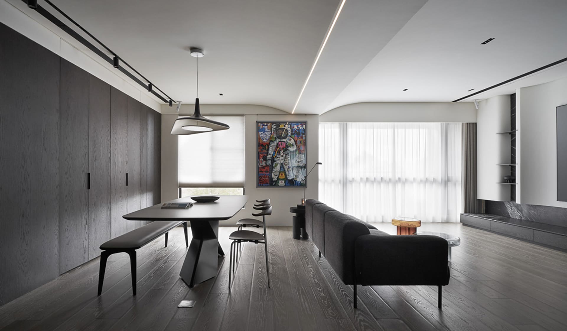 Modern minimalist living and dining room with dark wood flooring and light wood accents.