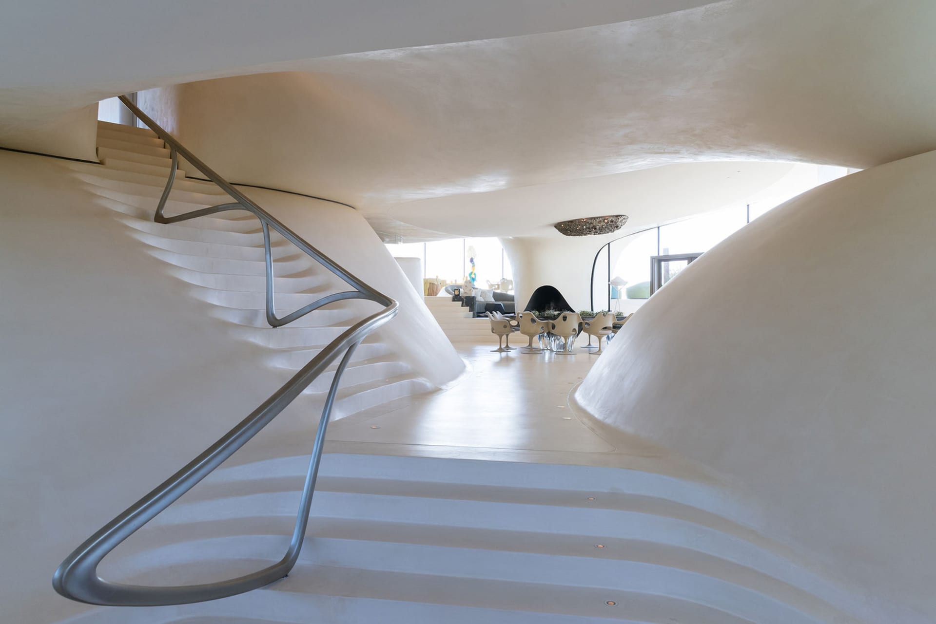 An interior view of a modern house with curved walls made of white concrete.