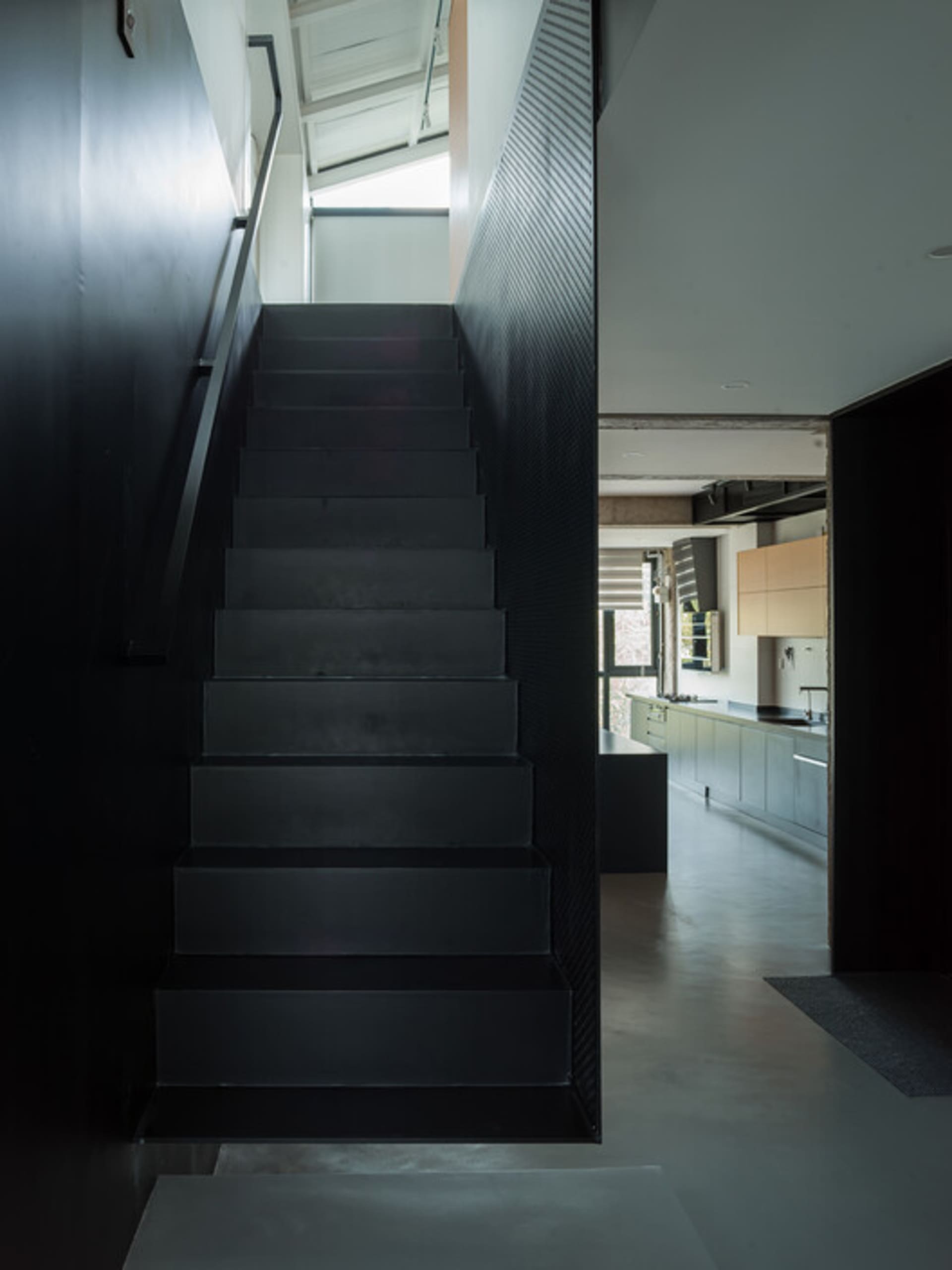A modern, black metal staircase in a residential interior with a minimalist design.