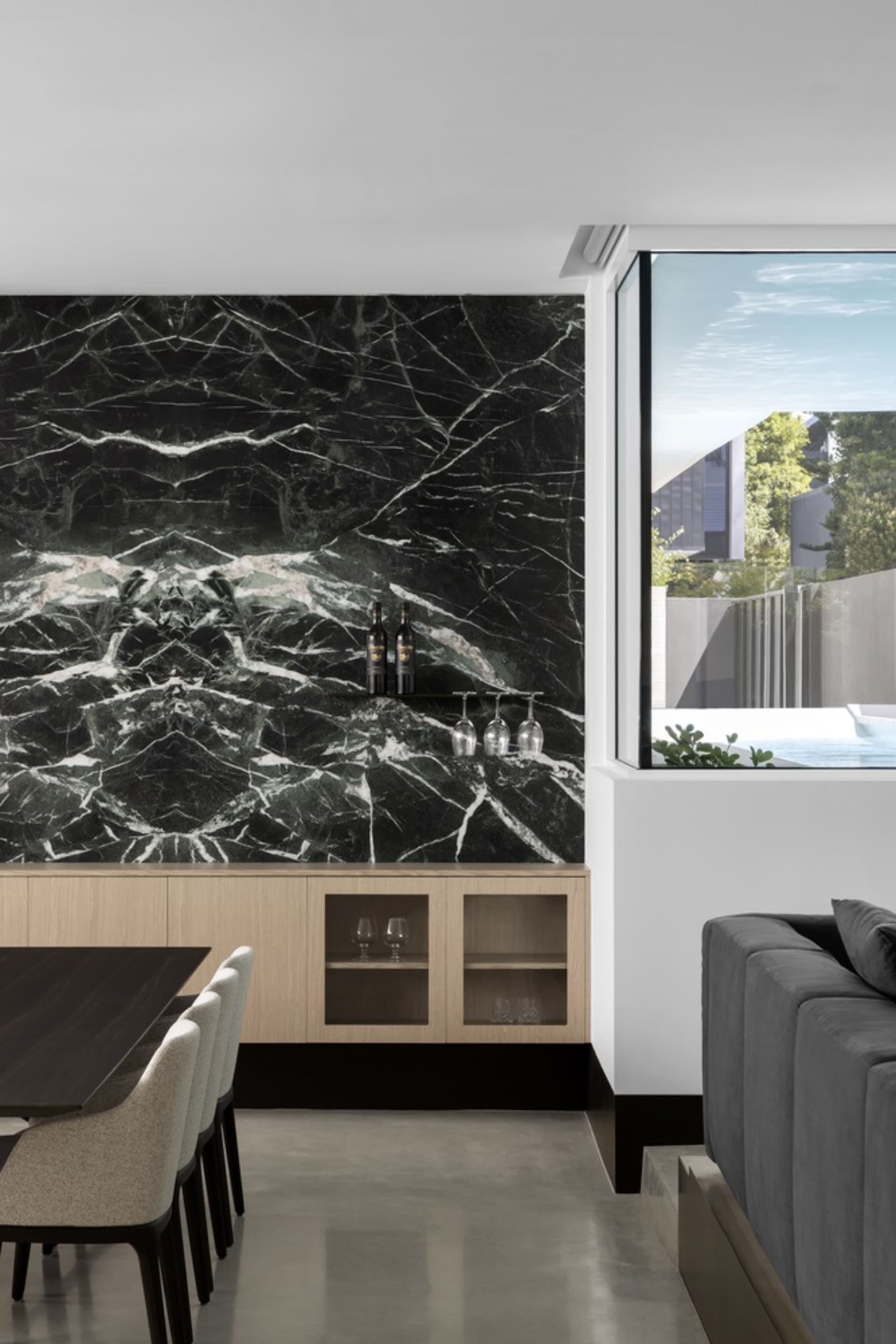 A modern kitchen featuring a black marble backsplash, wooden cabinets, and contemporary furniture.