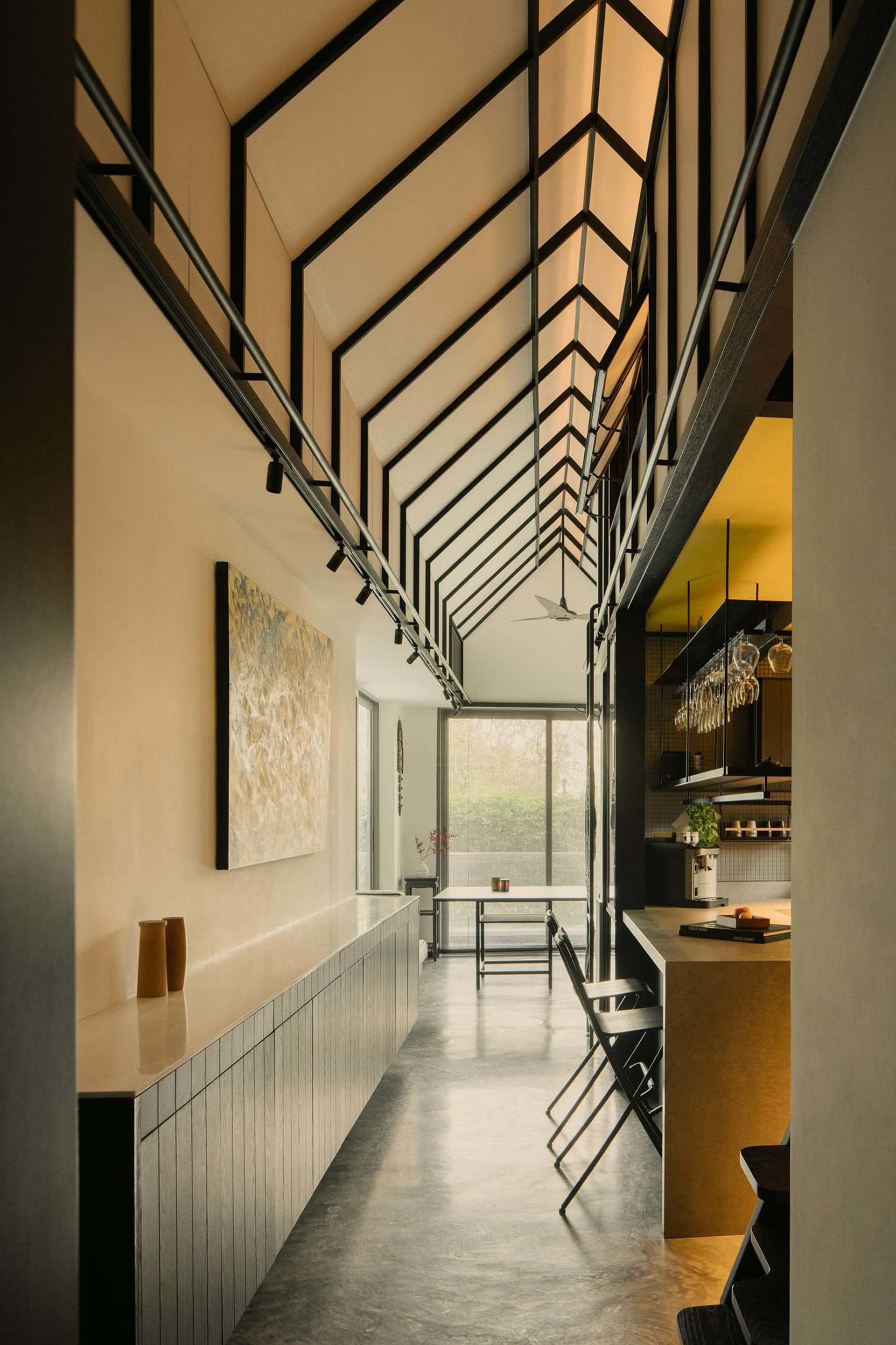 Modern residential entryway with concrete flooring, high ceiling, and industrial-style lighting.