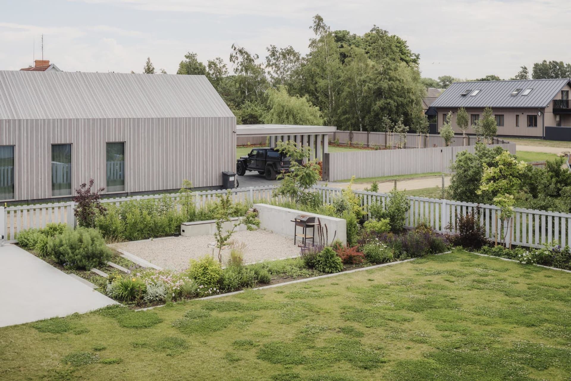 Modern residential exterior with wooden panels and metal roof and fence.