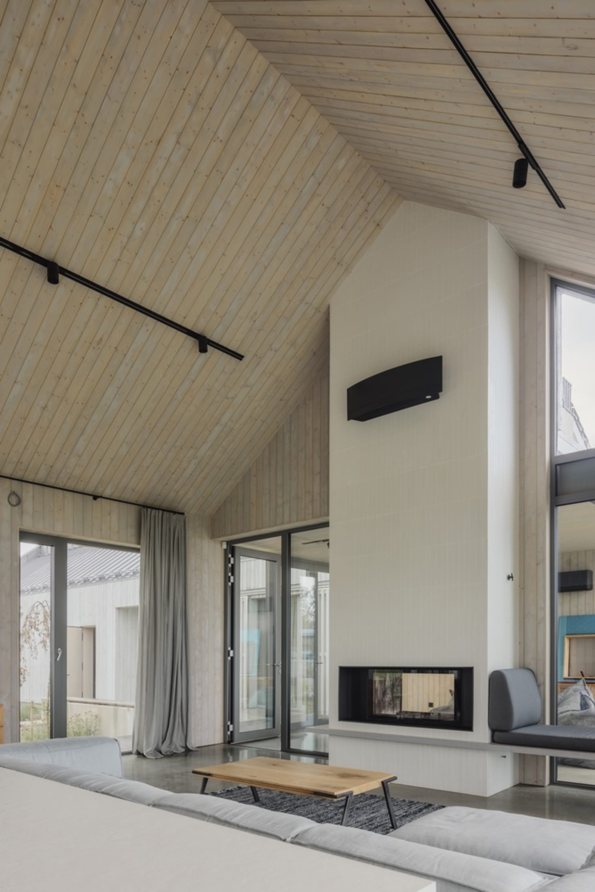 A modern living room featuring wood and concrete materials with a fireplace and seating area.
