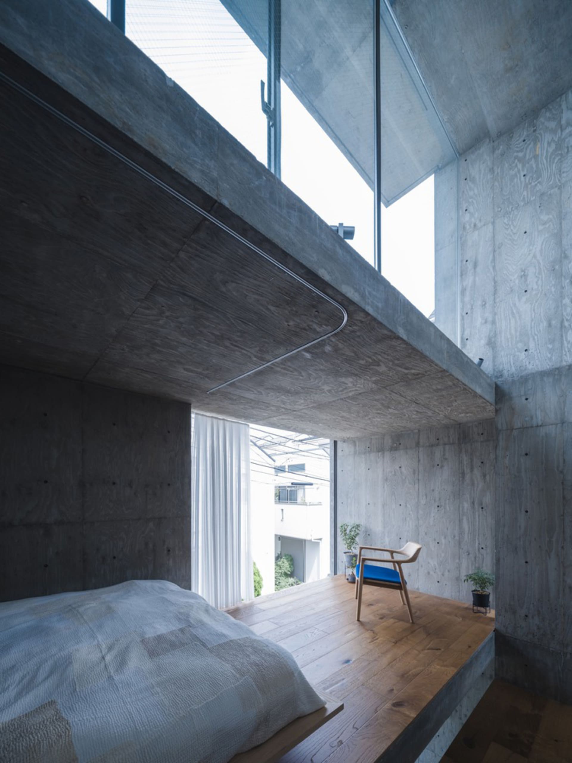 A modern bedroom with concrete walls and a wooden floor.