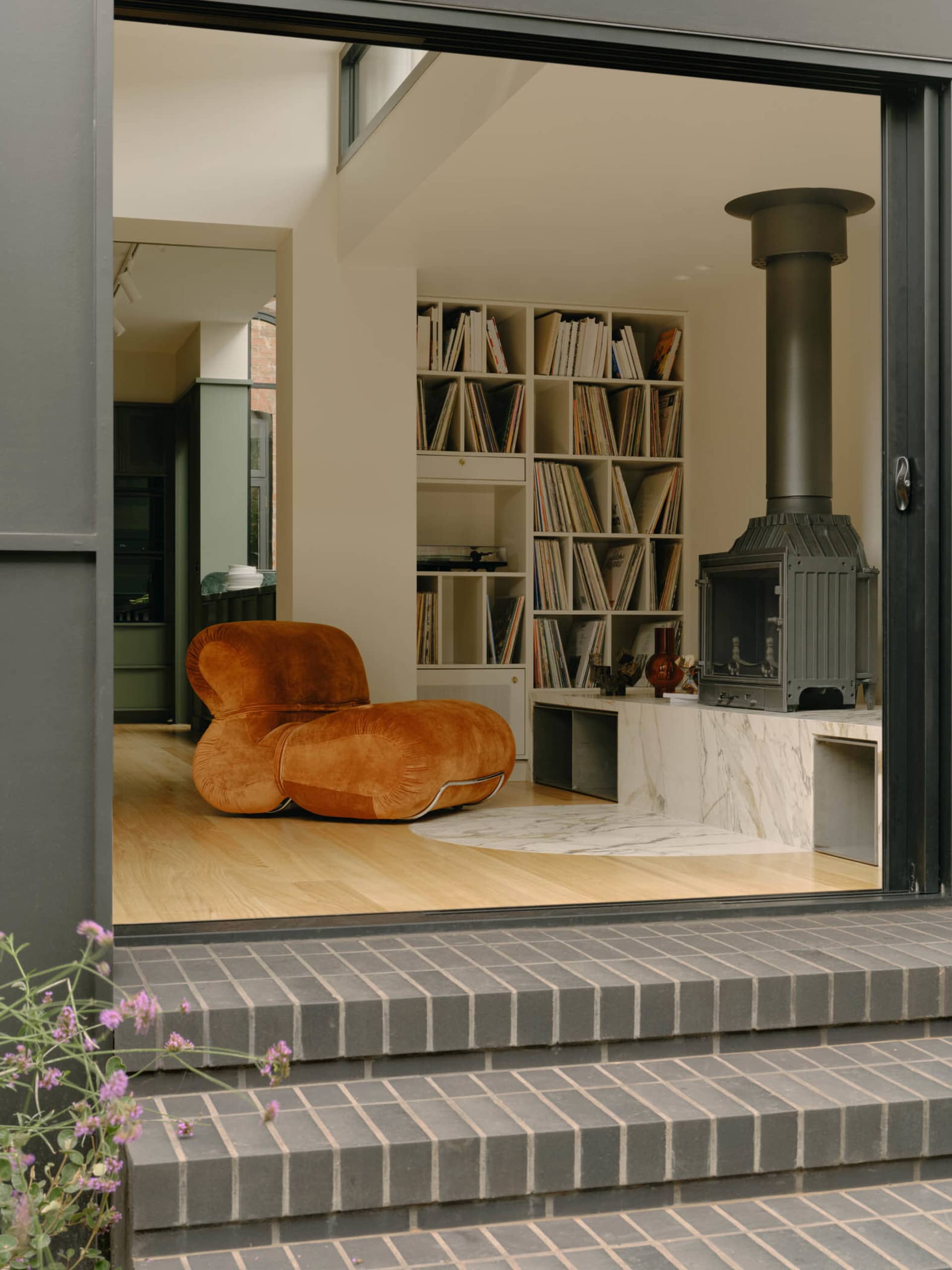 A cozy, industrial-style living room with a wooden floor, marble fireplace, and metal elements.
