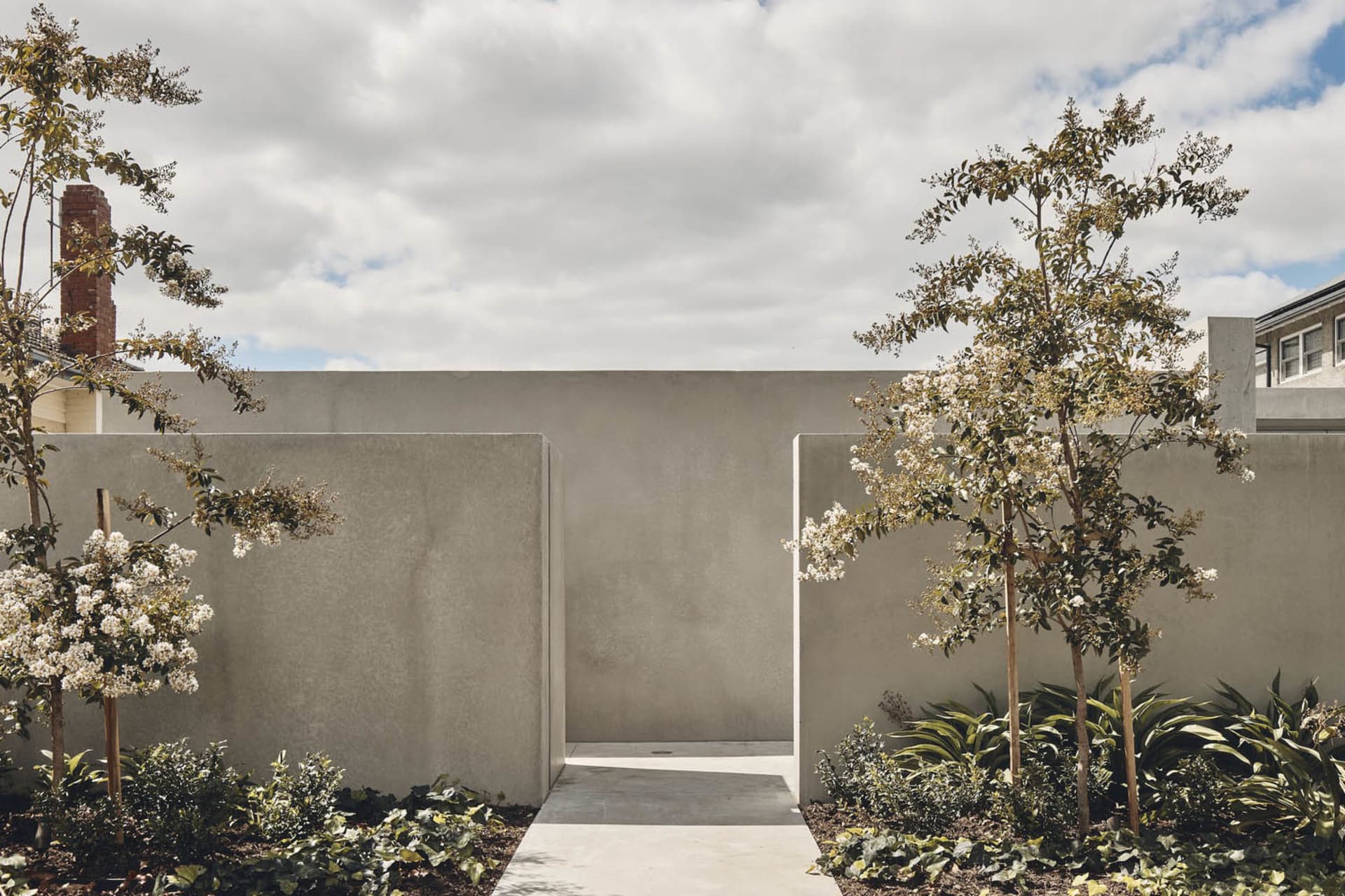 Concrete walls and pathway with flowering trees in a landscaped area.