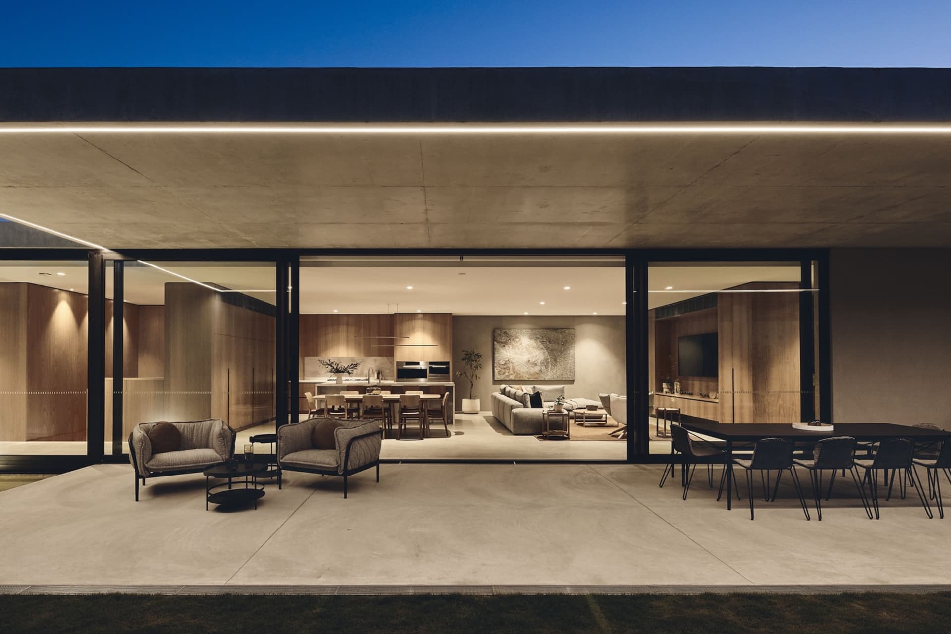 A modern concrete living area with sleek furniture and large windows.