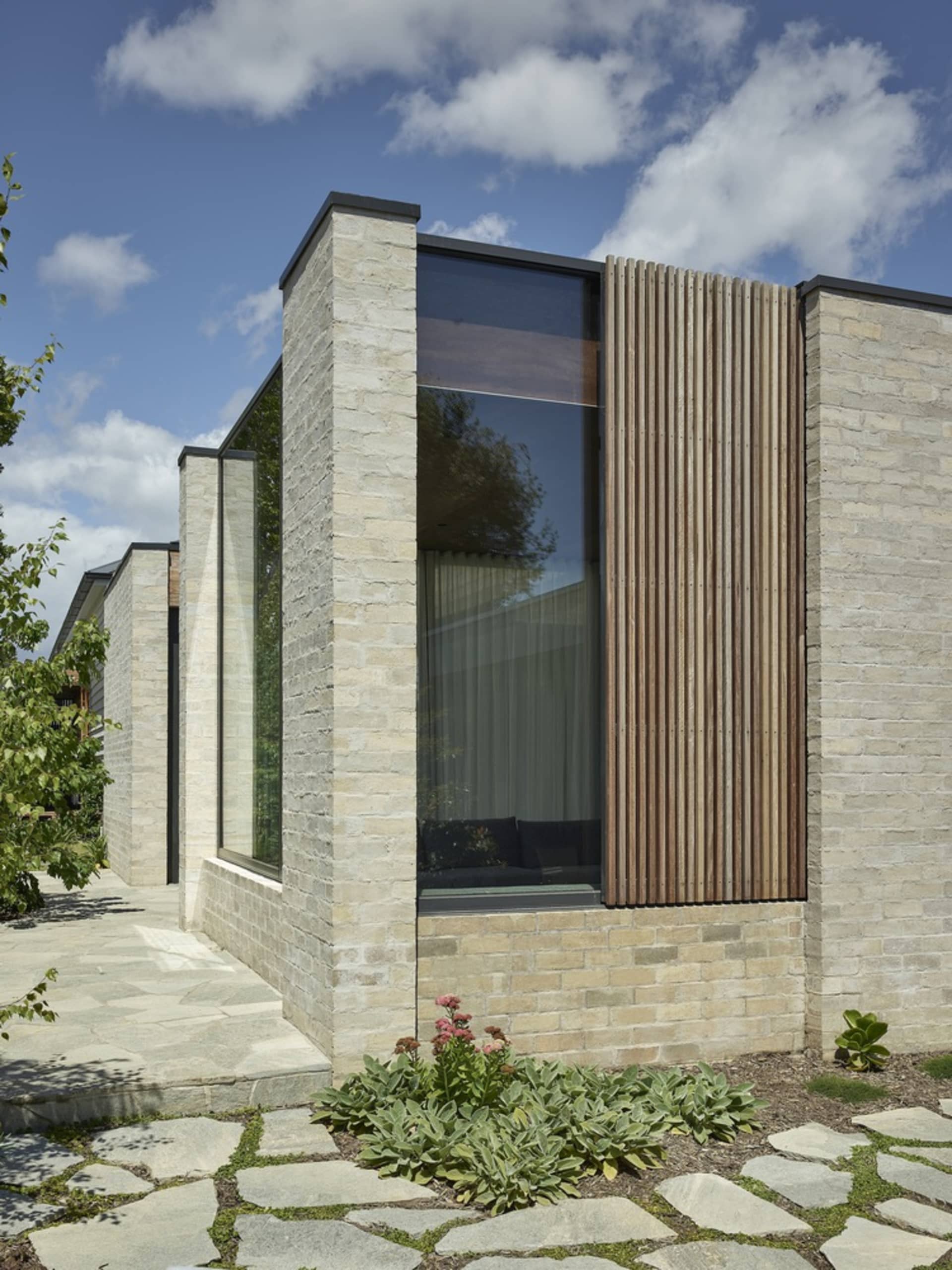 Modern house exterior featuring brick, glass, and wooden elements.
