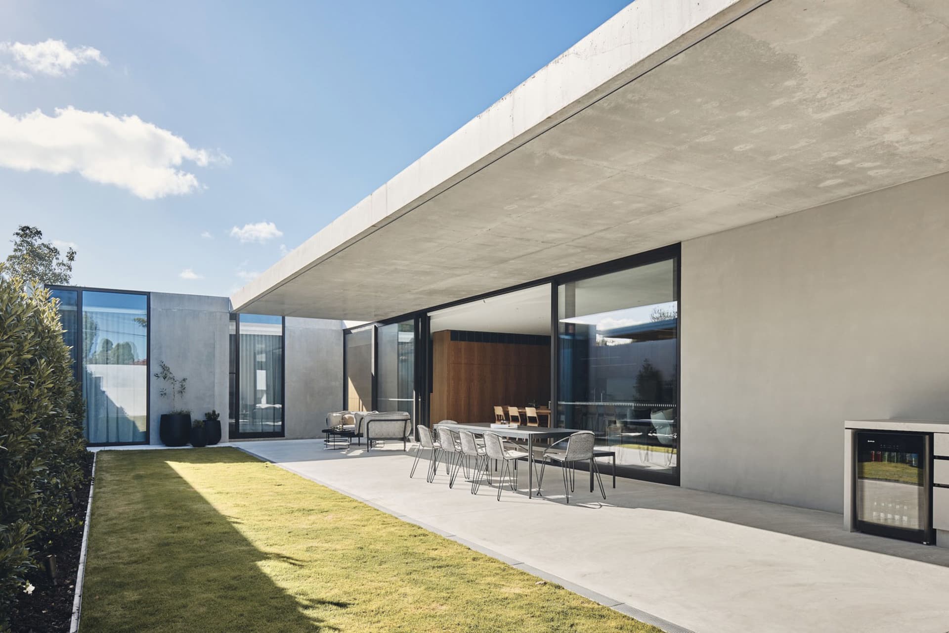 現代住宅建築採用混凝土外牆，搭配大型窗戶與戶外用餐區。