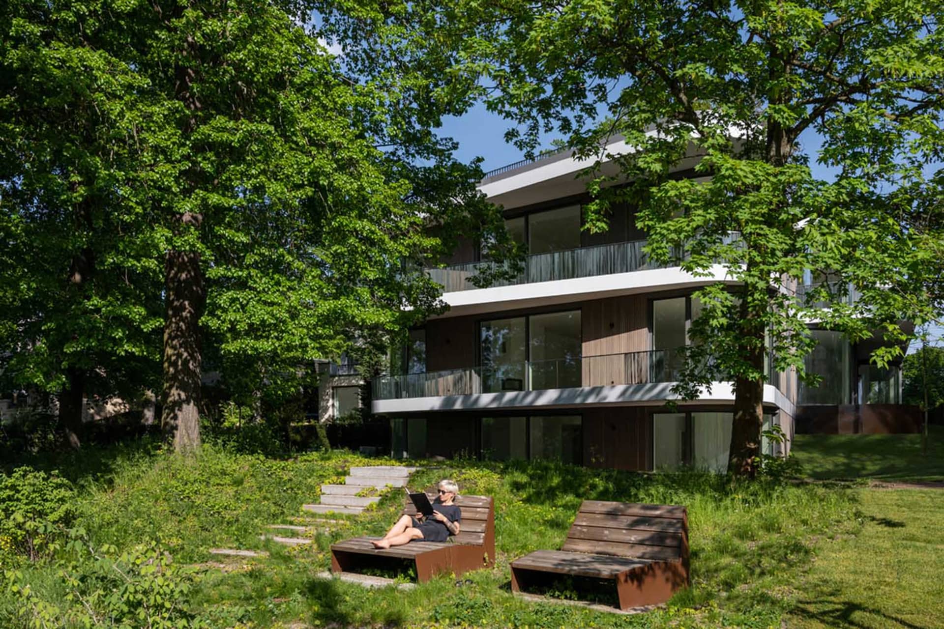 Modern residential building exterior with wooden accents, glass windows, and metal elements.