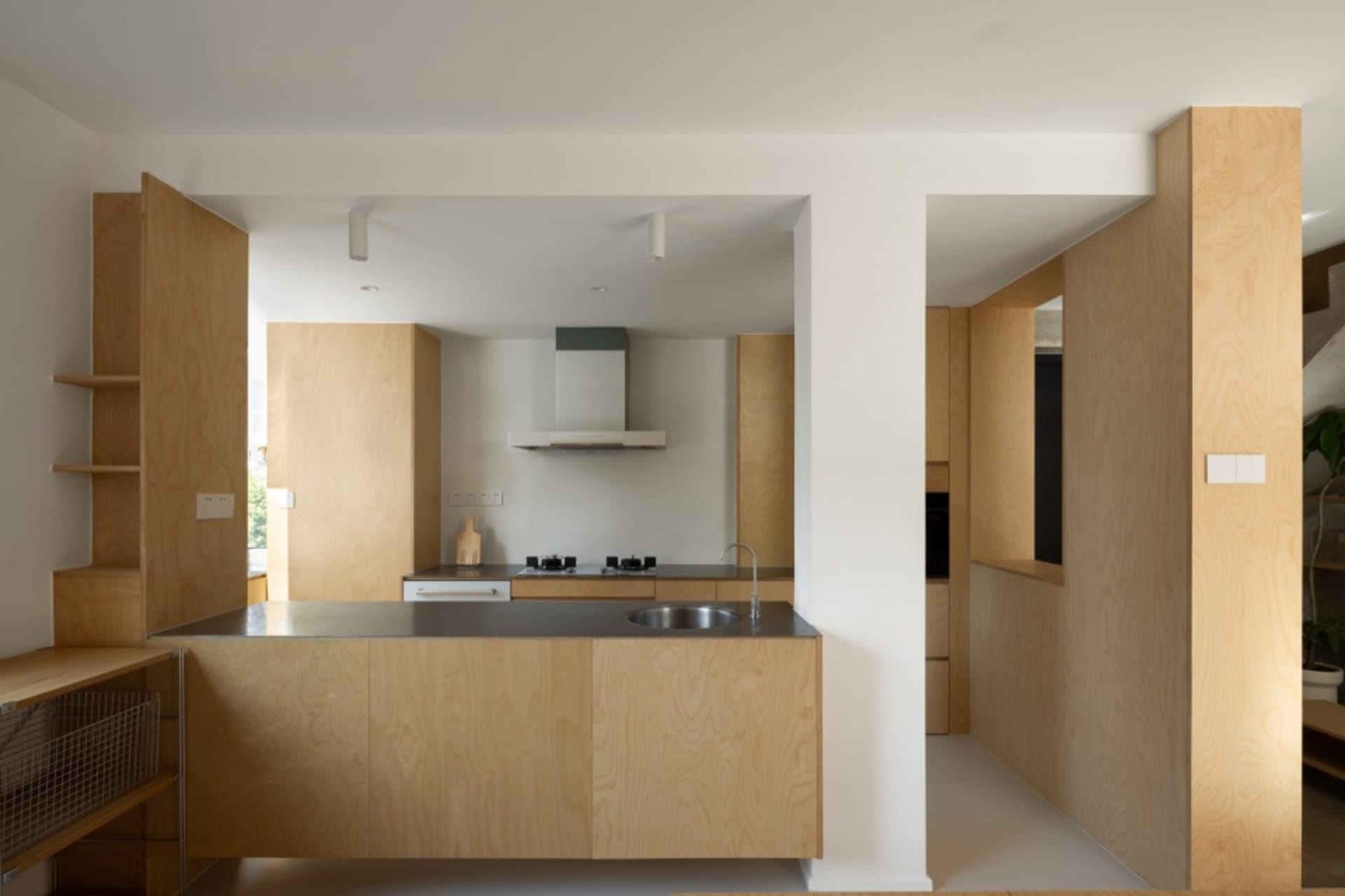 Modern minimalist kitchen with wooden cabinets and a stainless steel countertop.