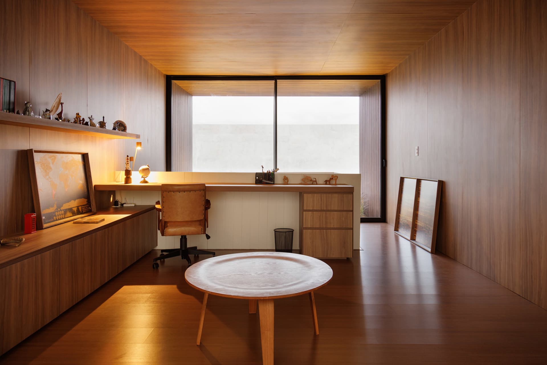 A modern office space featuring wooden interiors and a large desk with a chair.