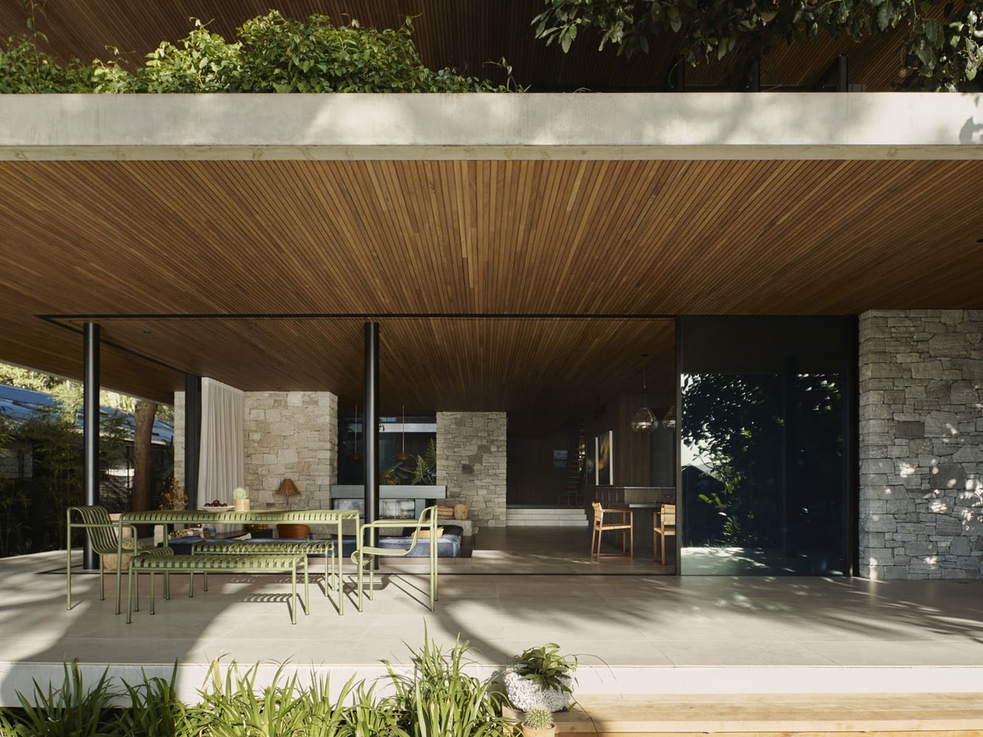Modern, minimalist residential patio featuring wood elements, stone walls, and concrete flooring.