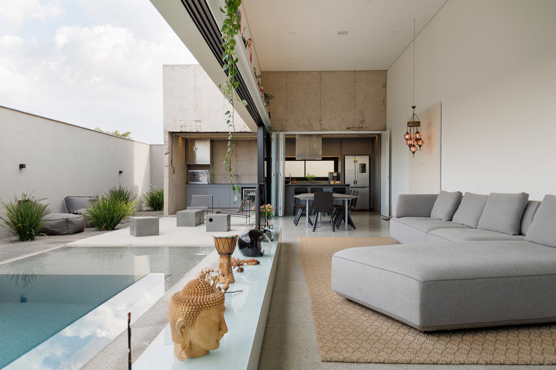 Contemporary living room featuring modern furniture and glass elements with concrete walls and floors.