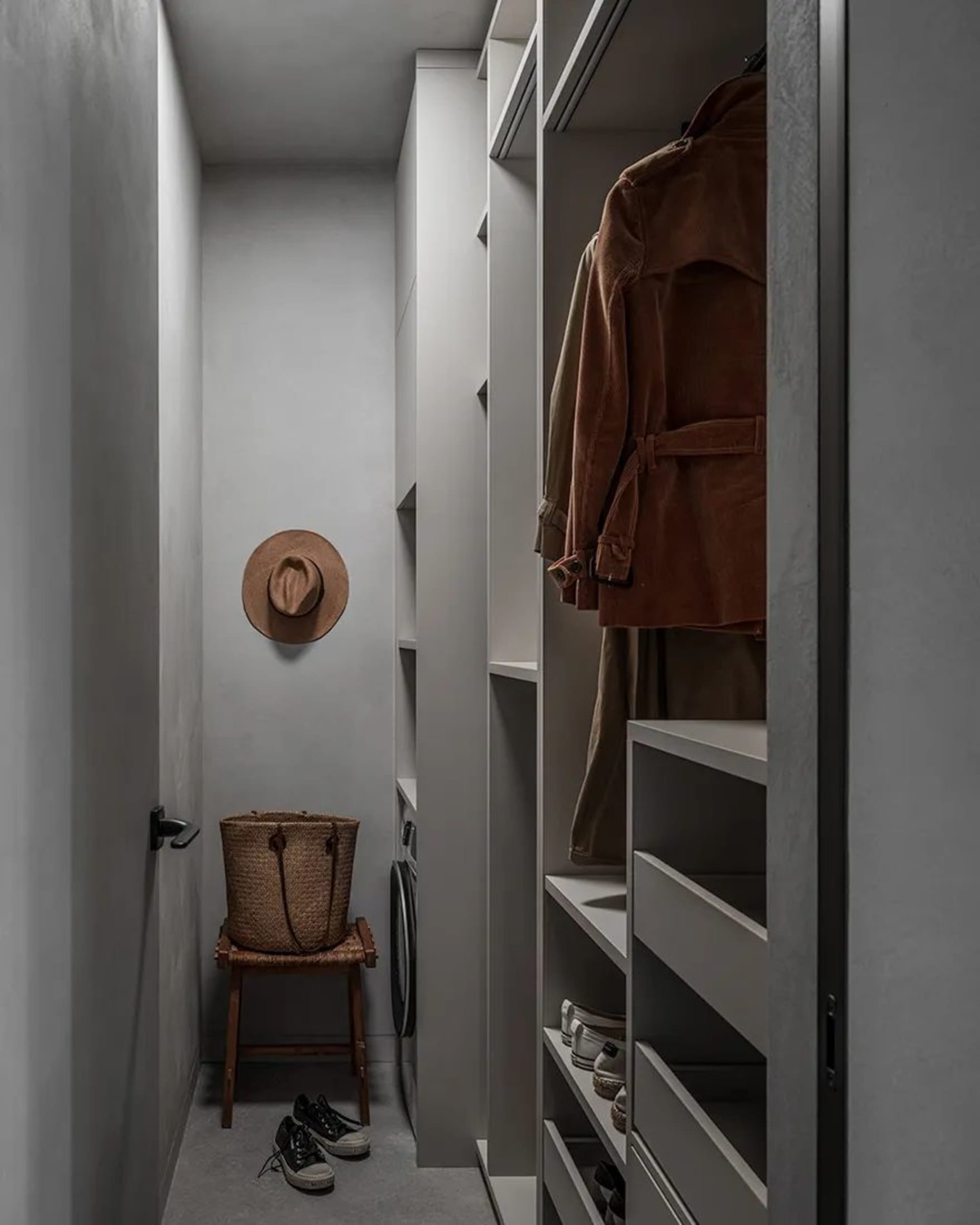 Modern minimalist closet with open shelves and a hanging jacket.
