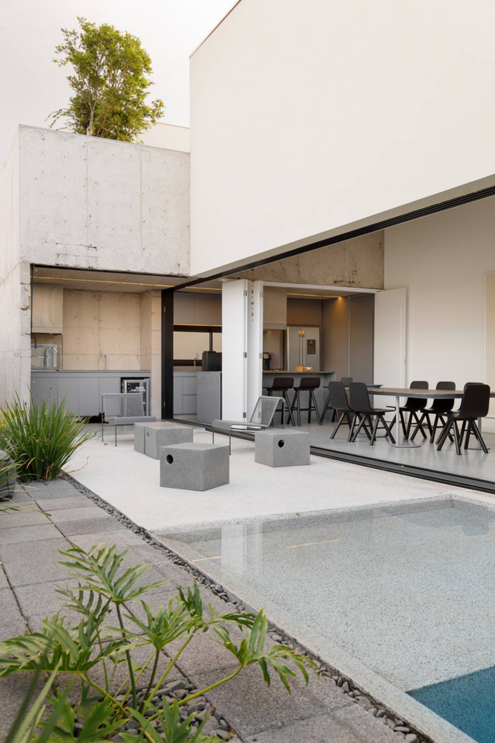 Modern outdoor residential area with concrete flooring, swimming pool, and kitchen area