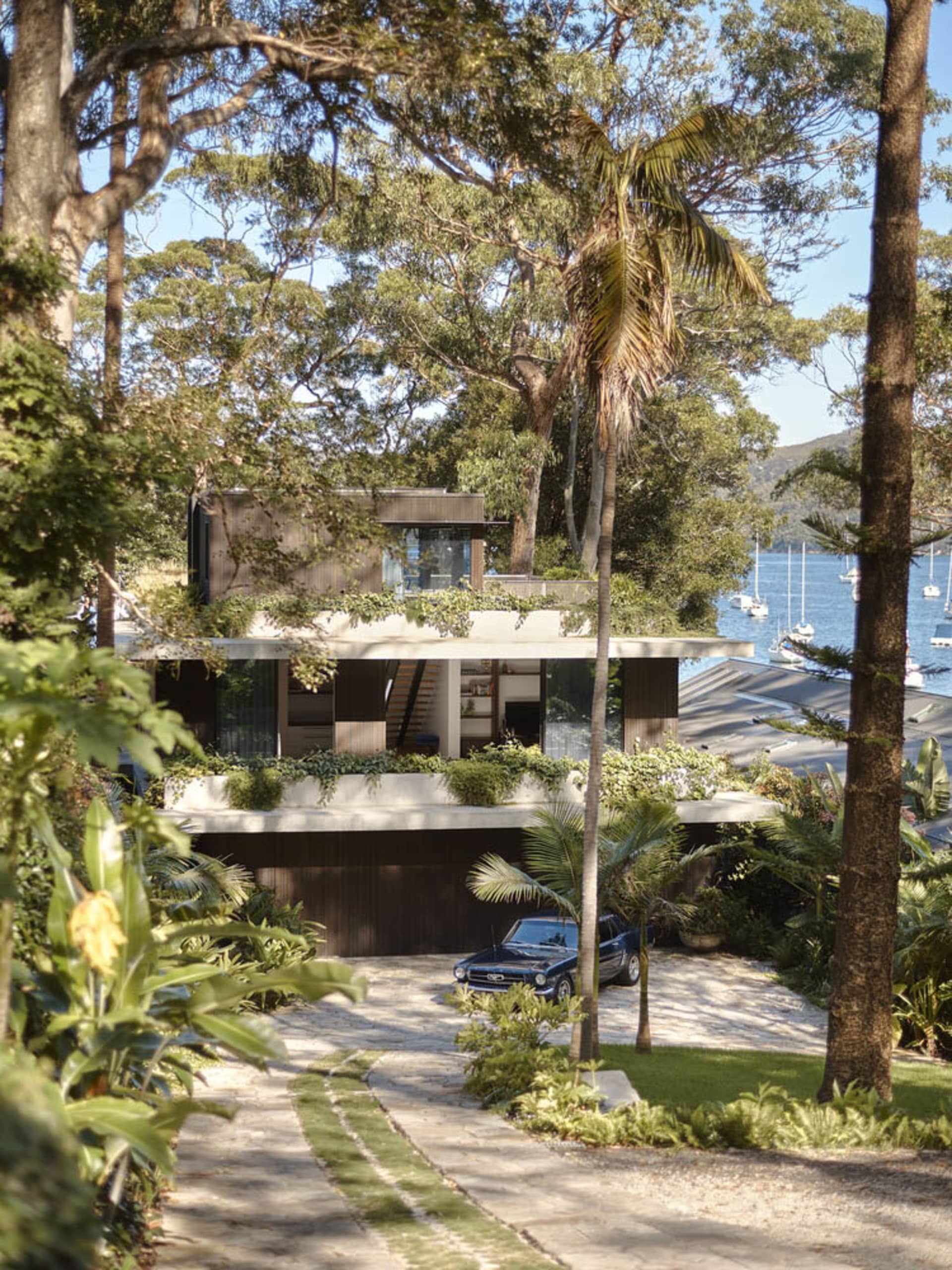 現代 waterfront 住宅採用石材、混凝土與玻璃外觀材料。