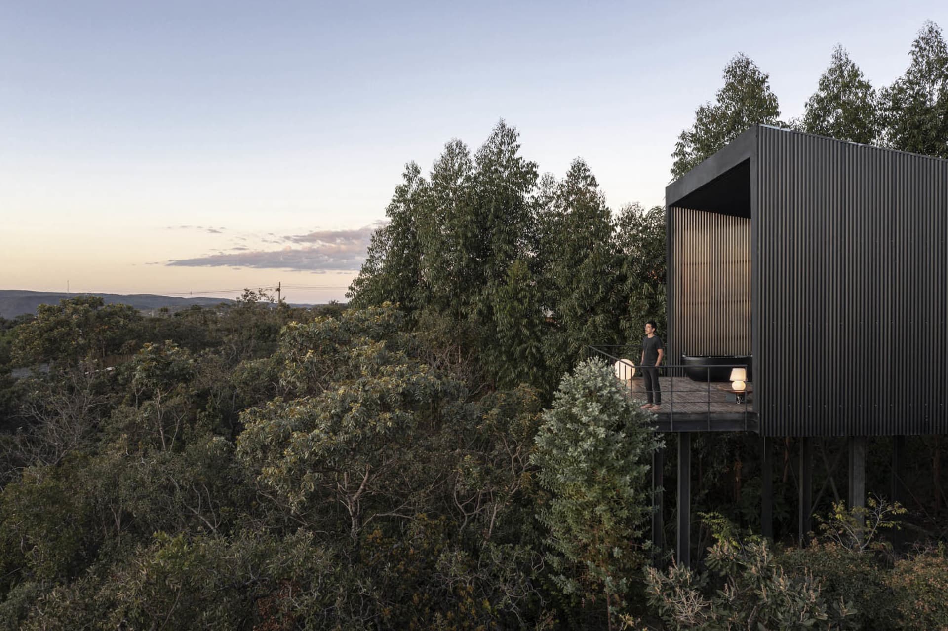 A modern, metal-clad building nestled in a forest.