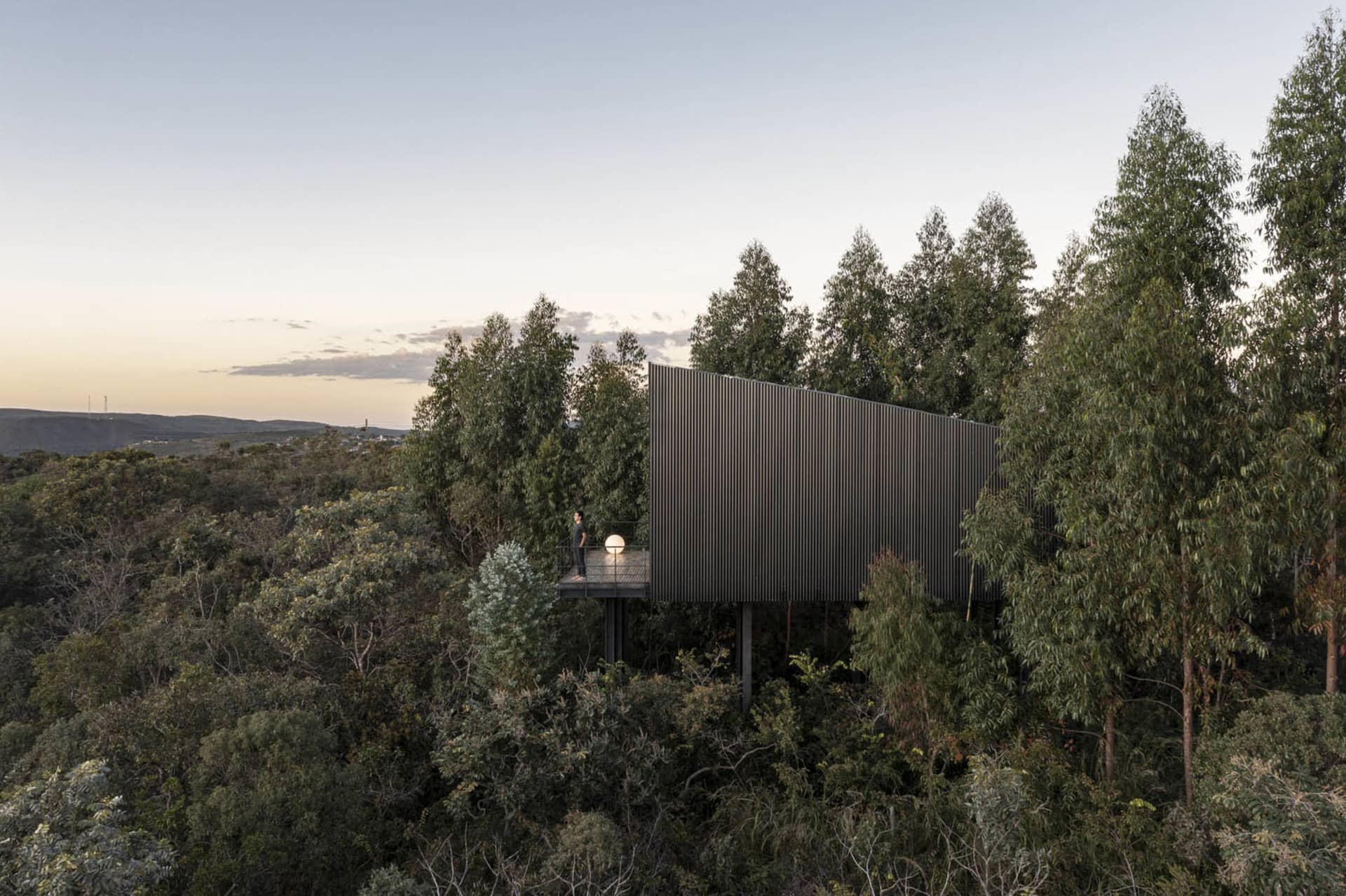 A modern home with a metal-clad exterior, surrounded by trees.