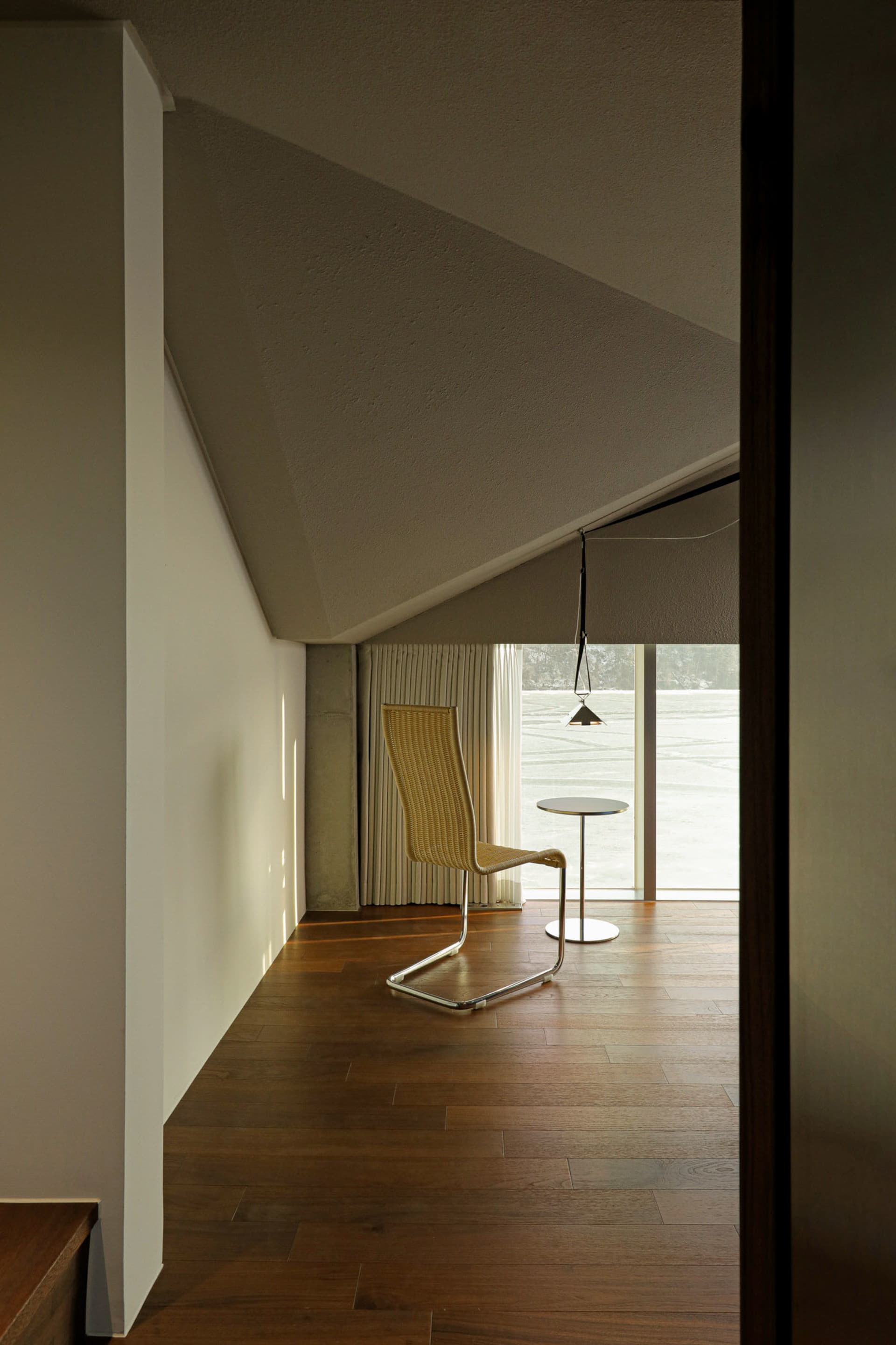Modern minimalist library with wooden flooring, glass walls, and metal accents.