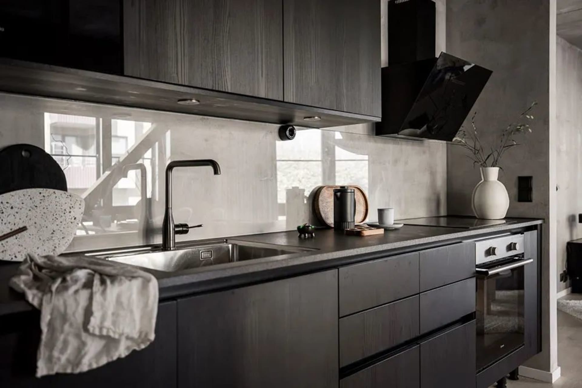 Kitchen with black wooden cabinets and a concrete backsplash.