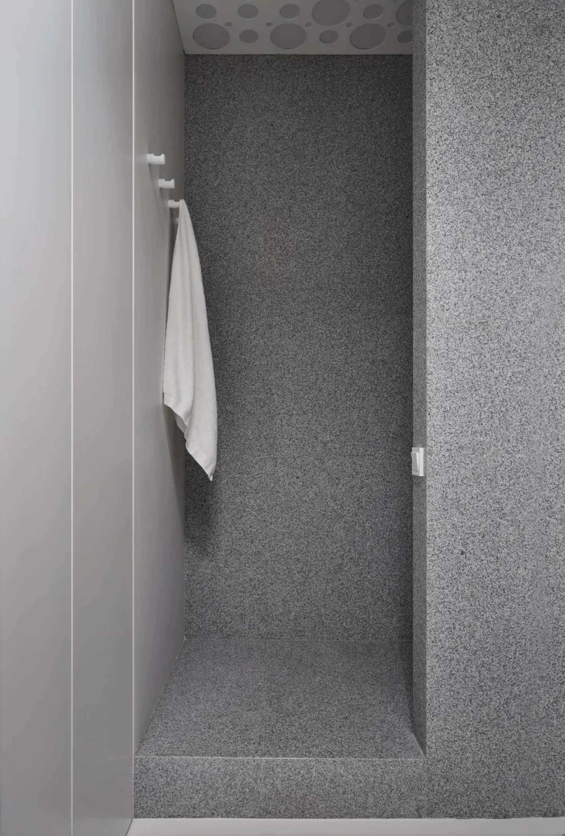 A modern bathroom with gray and concrete walls, featuring a towel hanging on a hook.