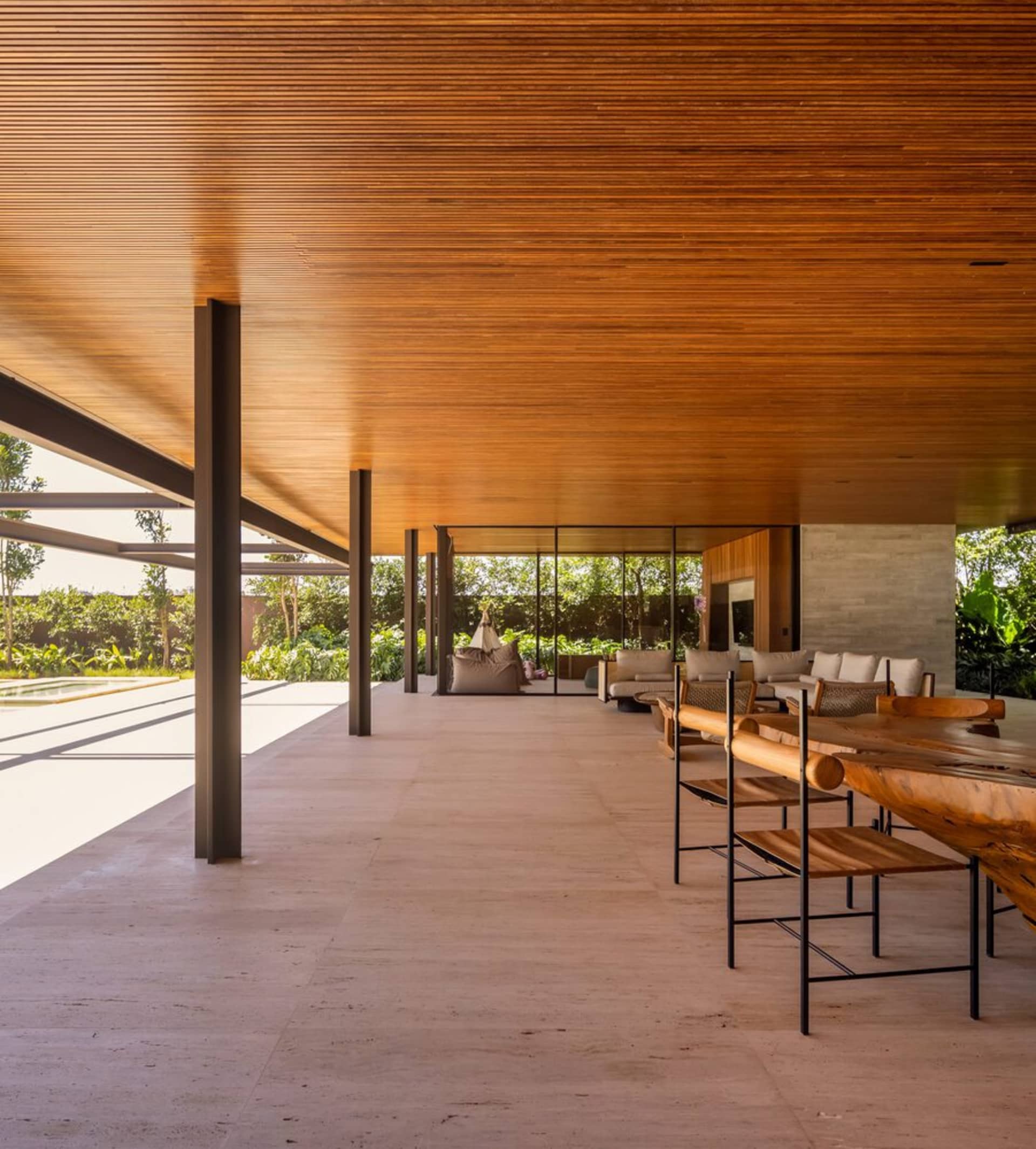A modern residential patio with a wooden ceiling and seating area.