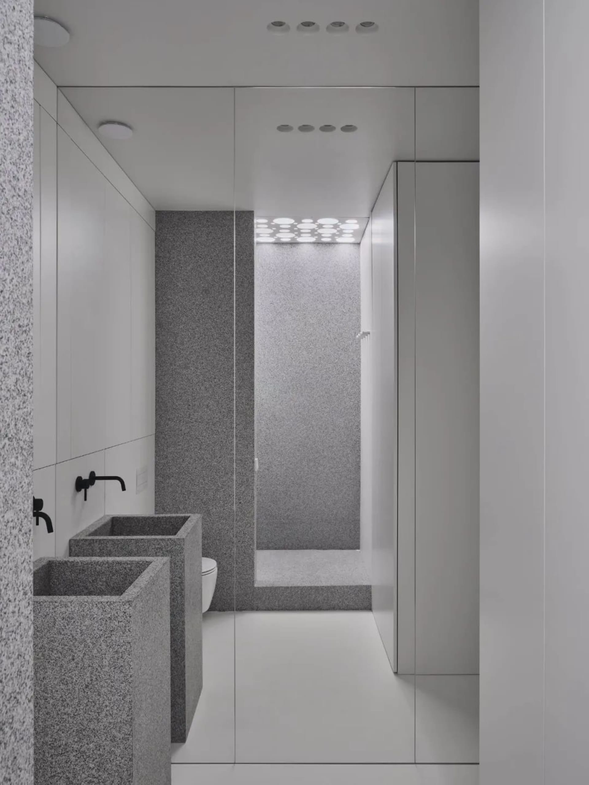 Minimalist grey granite bathroom interior with white floor and black fixtures