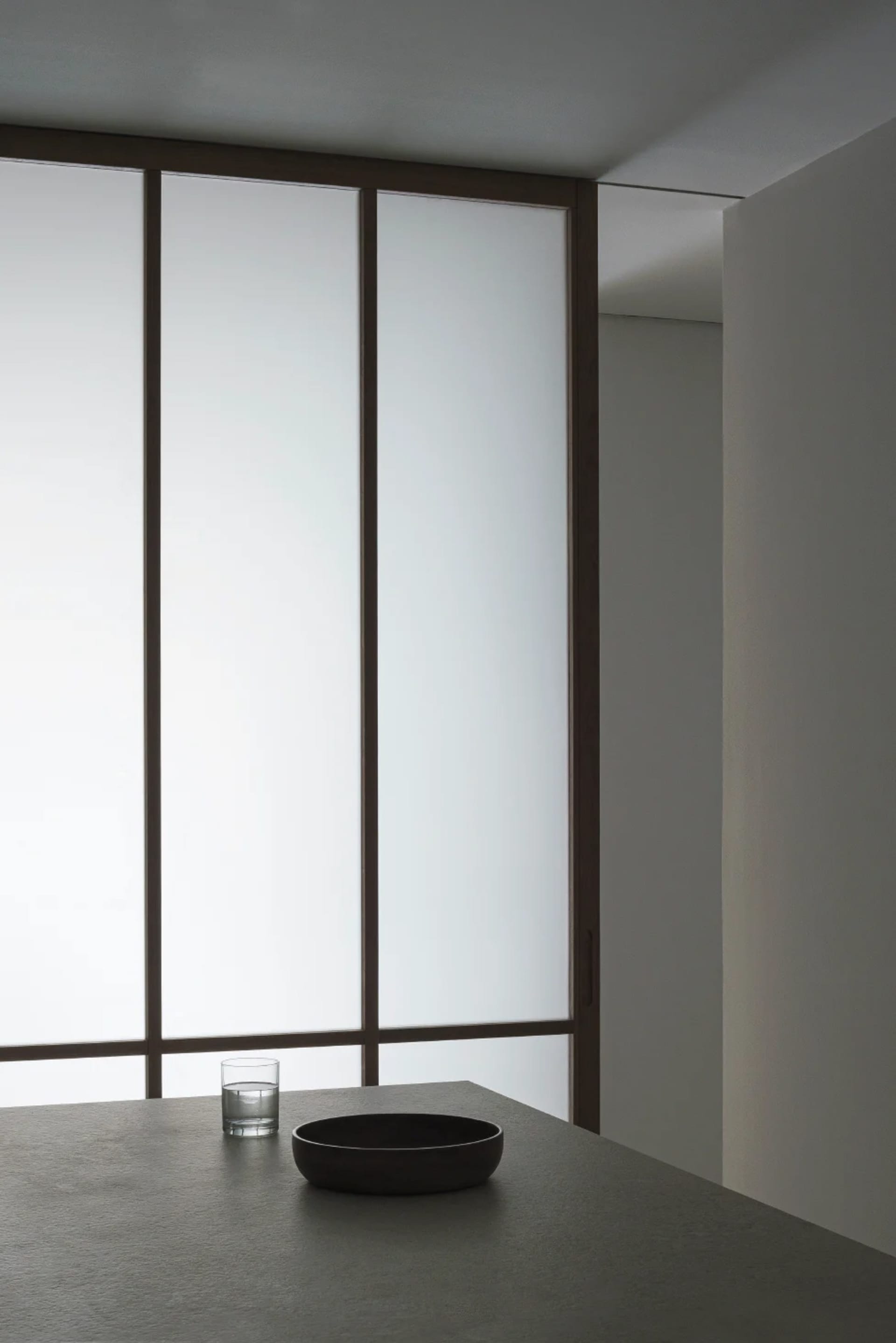 Minimalist room with large windows and glass surfaces.