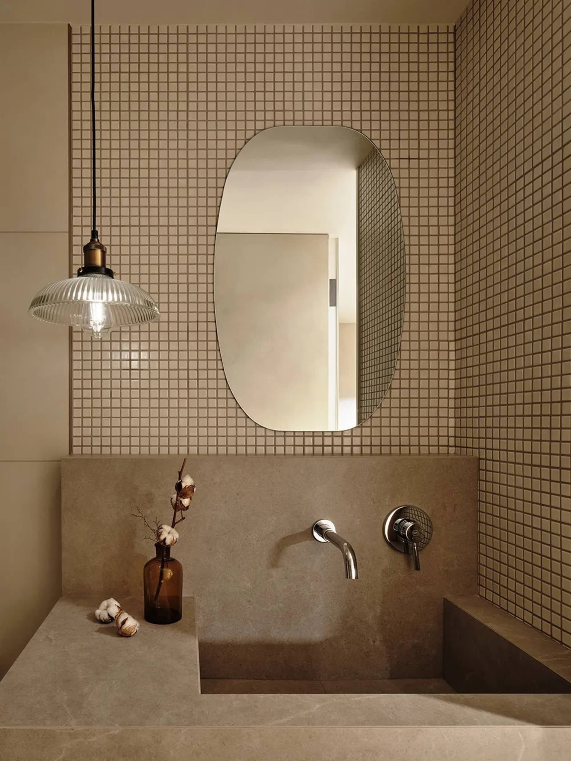 A minimalist bathroom with concrete walls, a tiled floor, and a glass pendant light fixture.