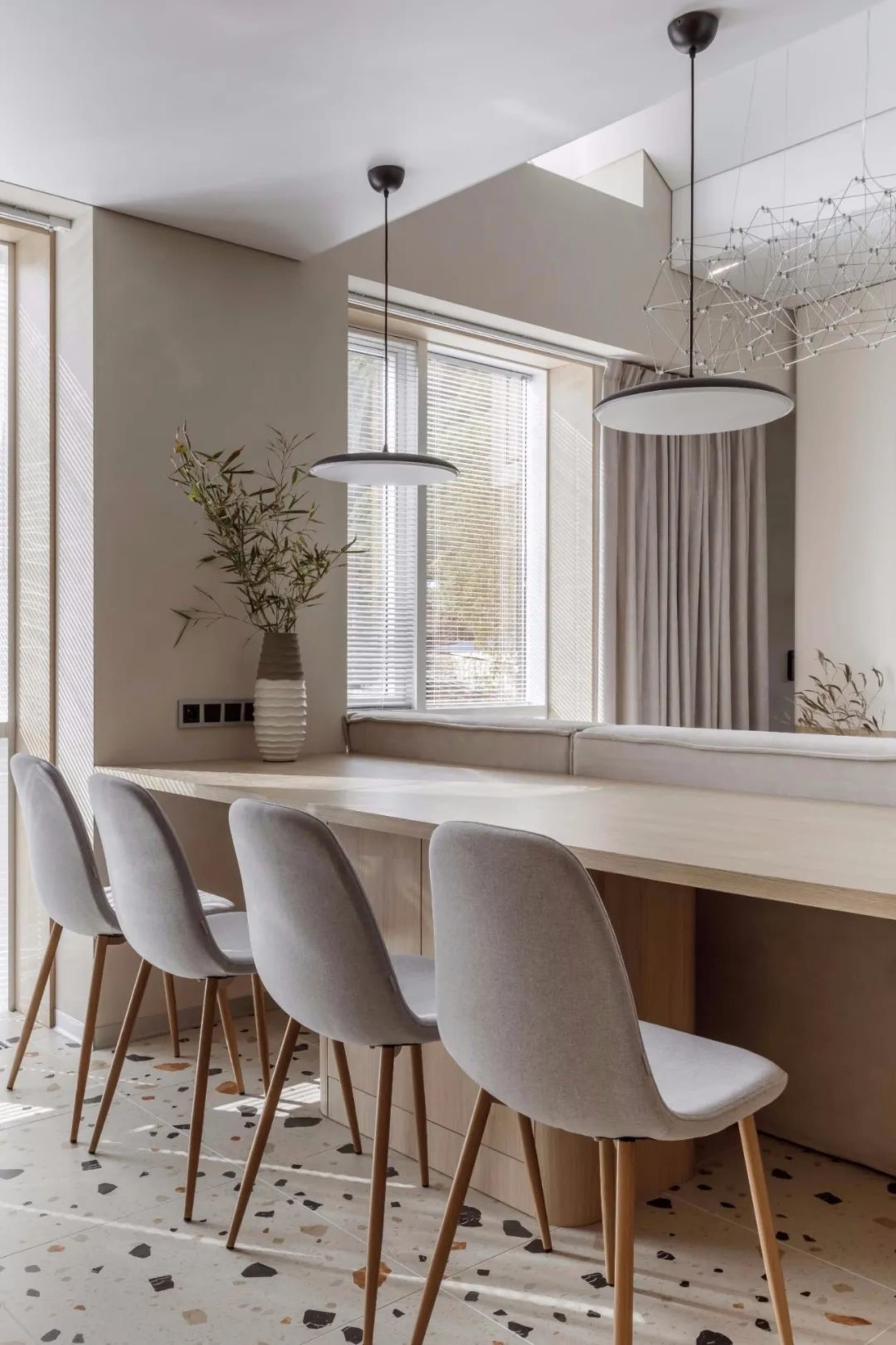 Modern dining area with terrazzo floor, wooden table, and upholstered chairs