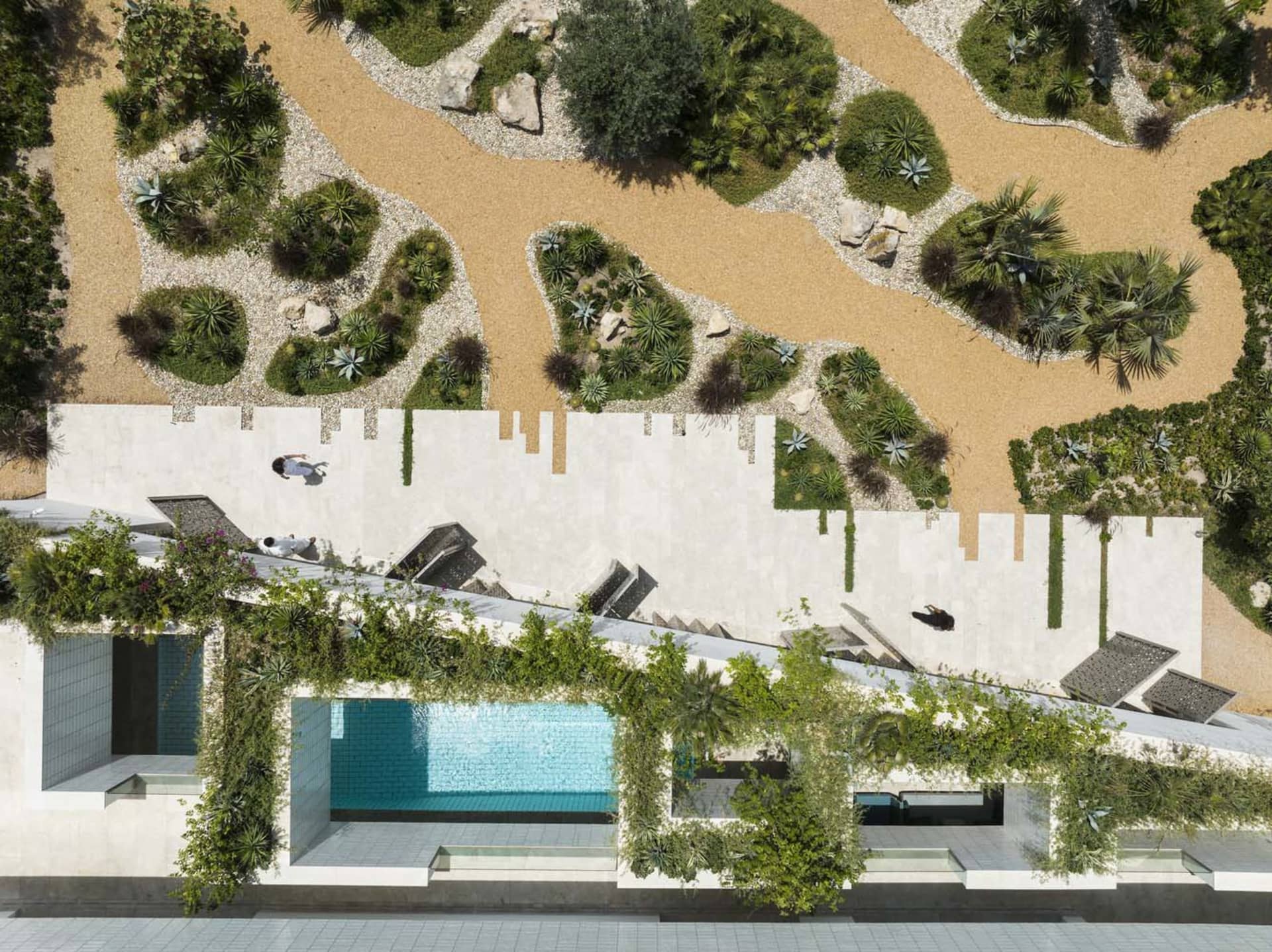 A modern residential exterior with a concrete facade and rock pathway.