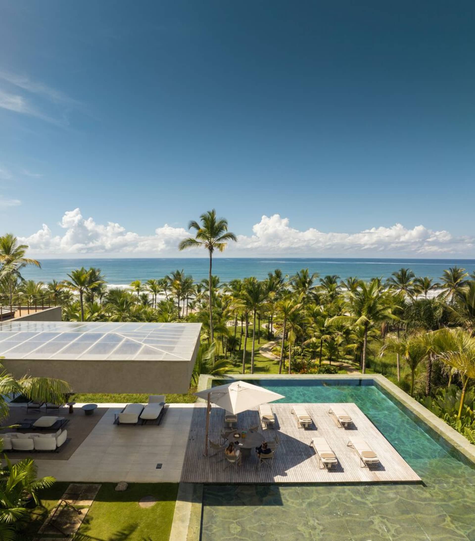 Modern residential architecture featuring a glass pool with a beach view.