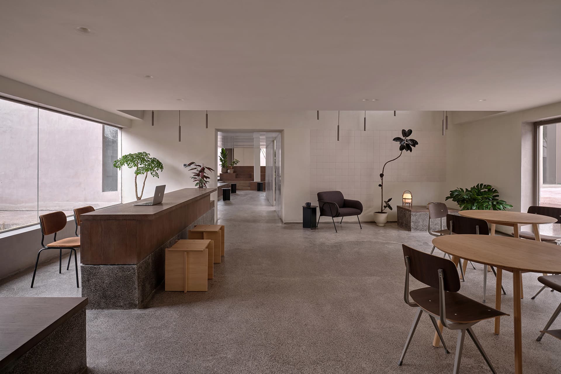 Modern, minimalist coffee shop interior with concrete flooring and contemporary furniture.