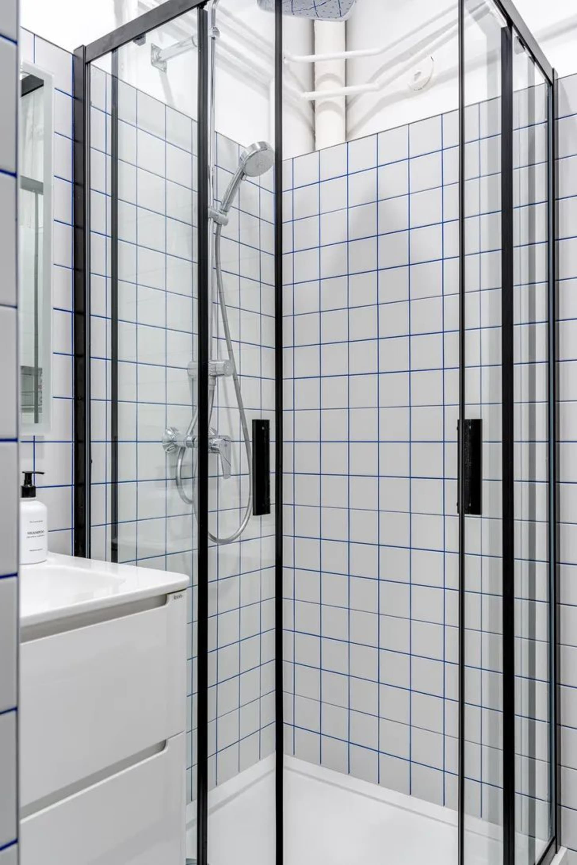 Modern minimalist bathroom featuring ceramic tiles, sleek glass shower enclosure, and integrated vanity unit.