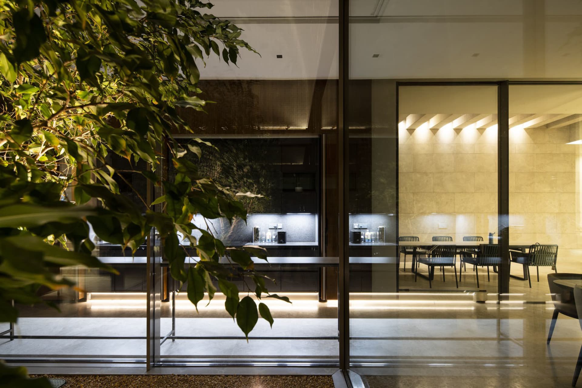 A modern residential dining area featuring concrete, glass, and metal elements.