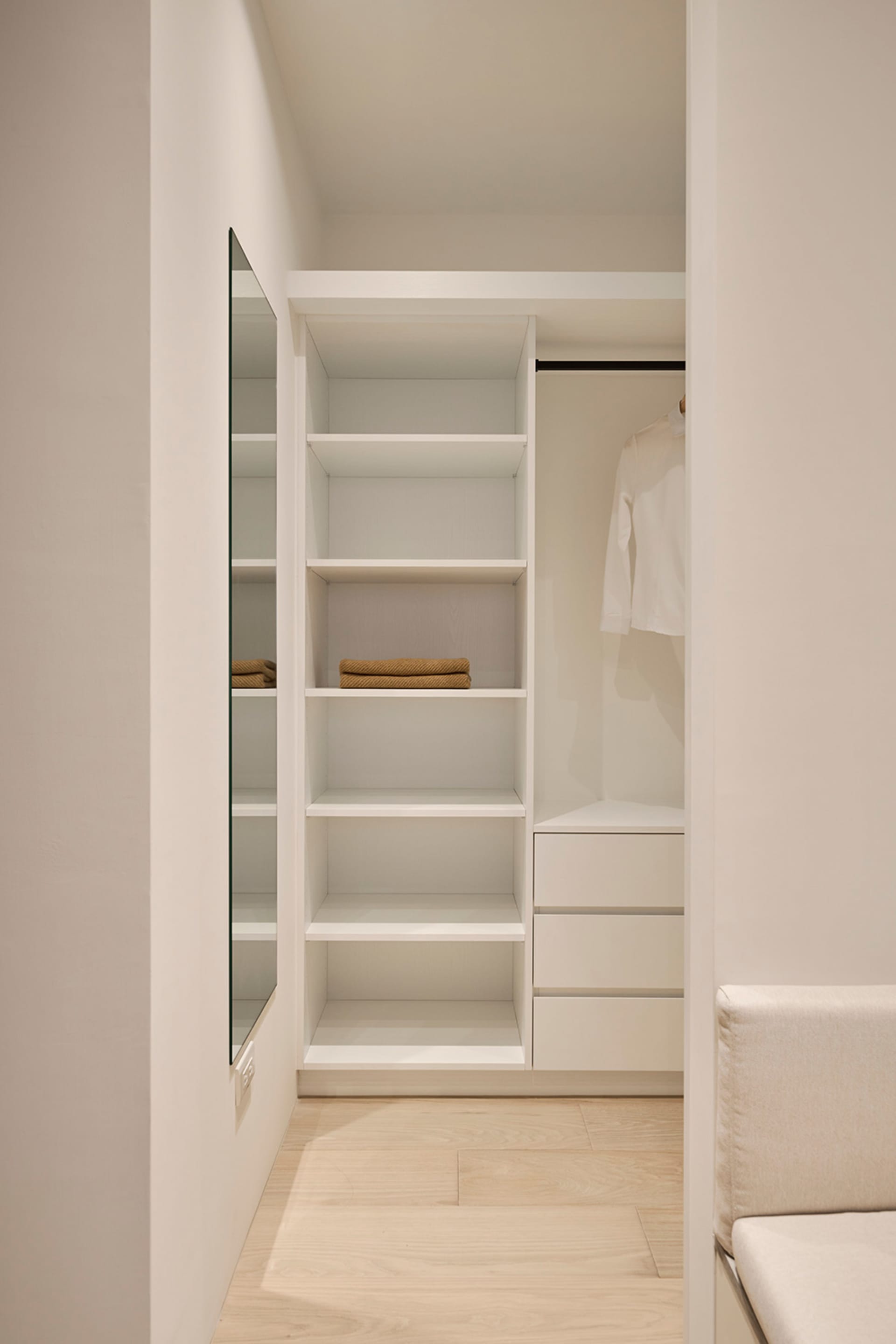 An organized closet with white wood shelves and drawers, showcasing a minimalist design.