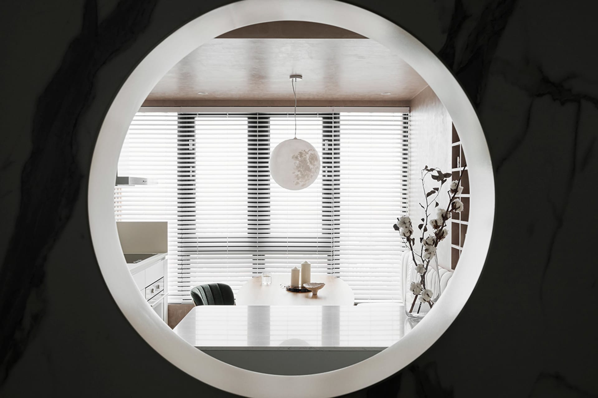 Modern, minimalist residential dining room with white decor and white pendant light hanging from the ceiling.