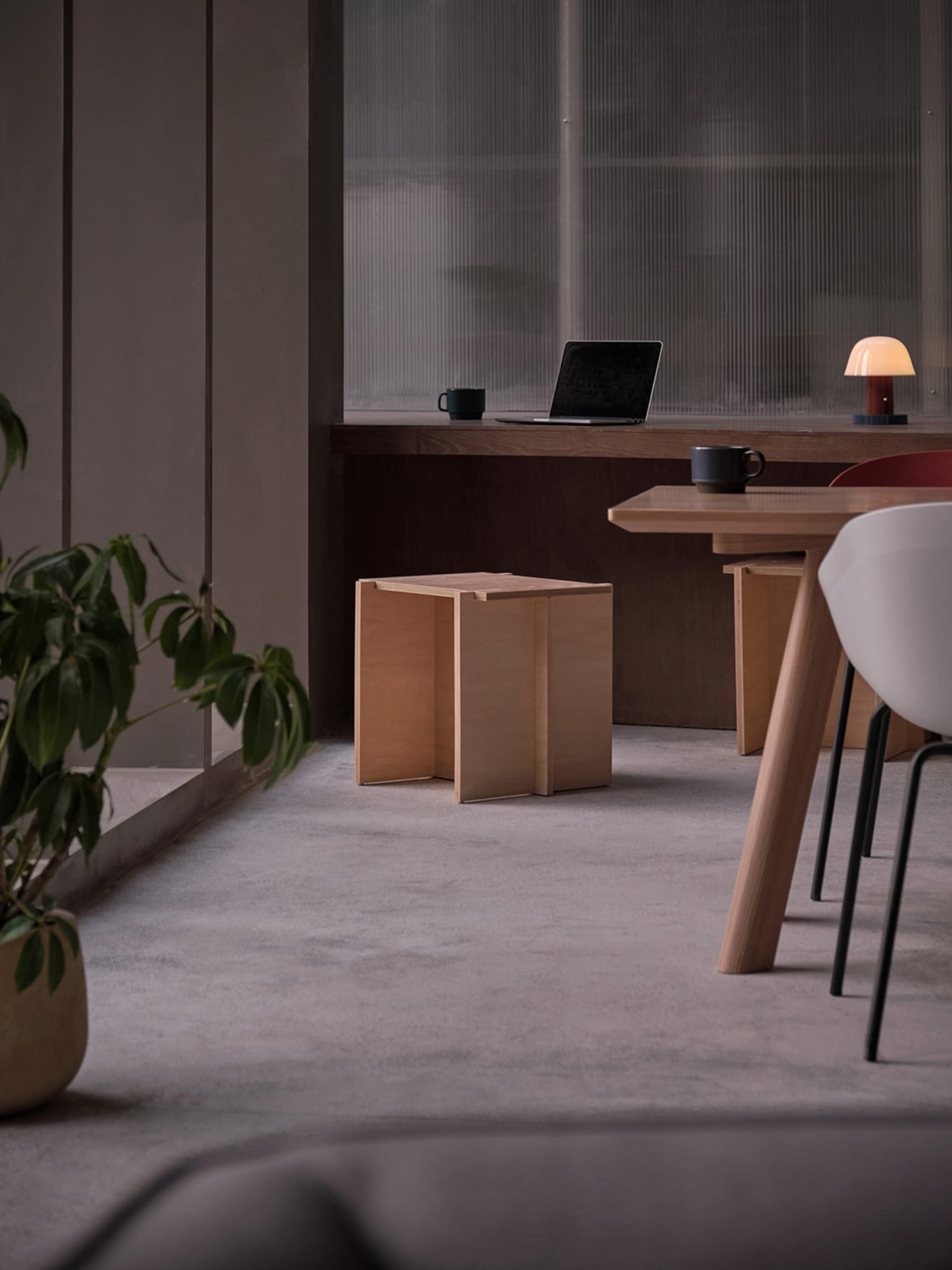 A modern home office space featuring minimalist design with wooden furniture and a laptop on a desk.