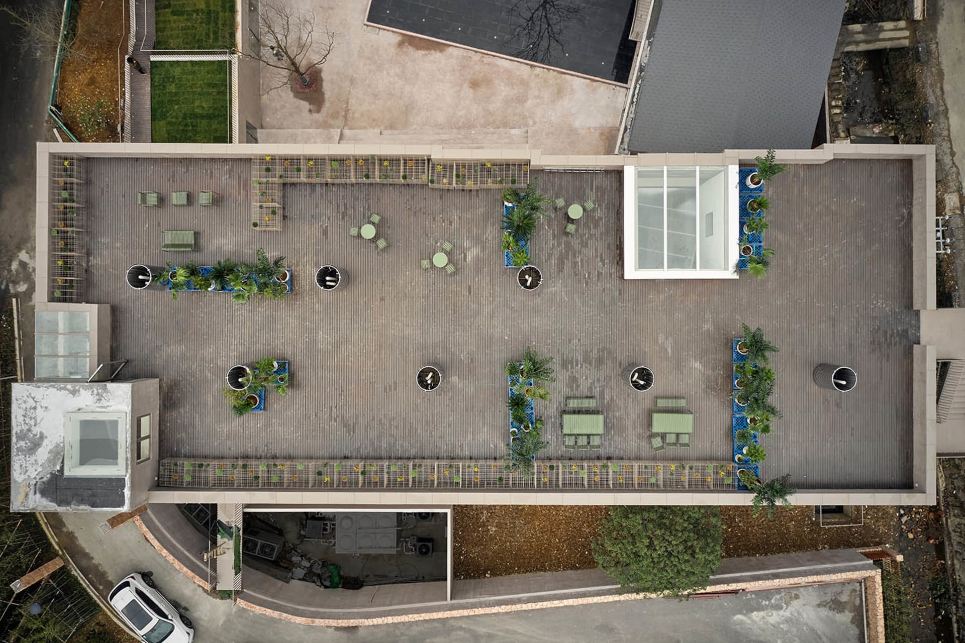 Aerial view of a modern wooden patio with potted plants, outdoor furniture, and a transparent glass wall.
