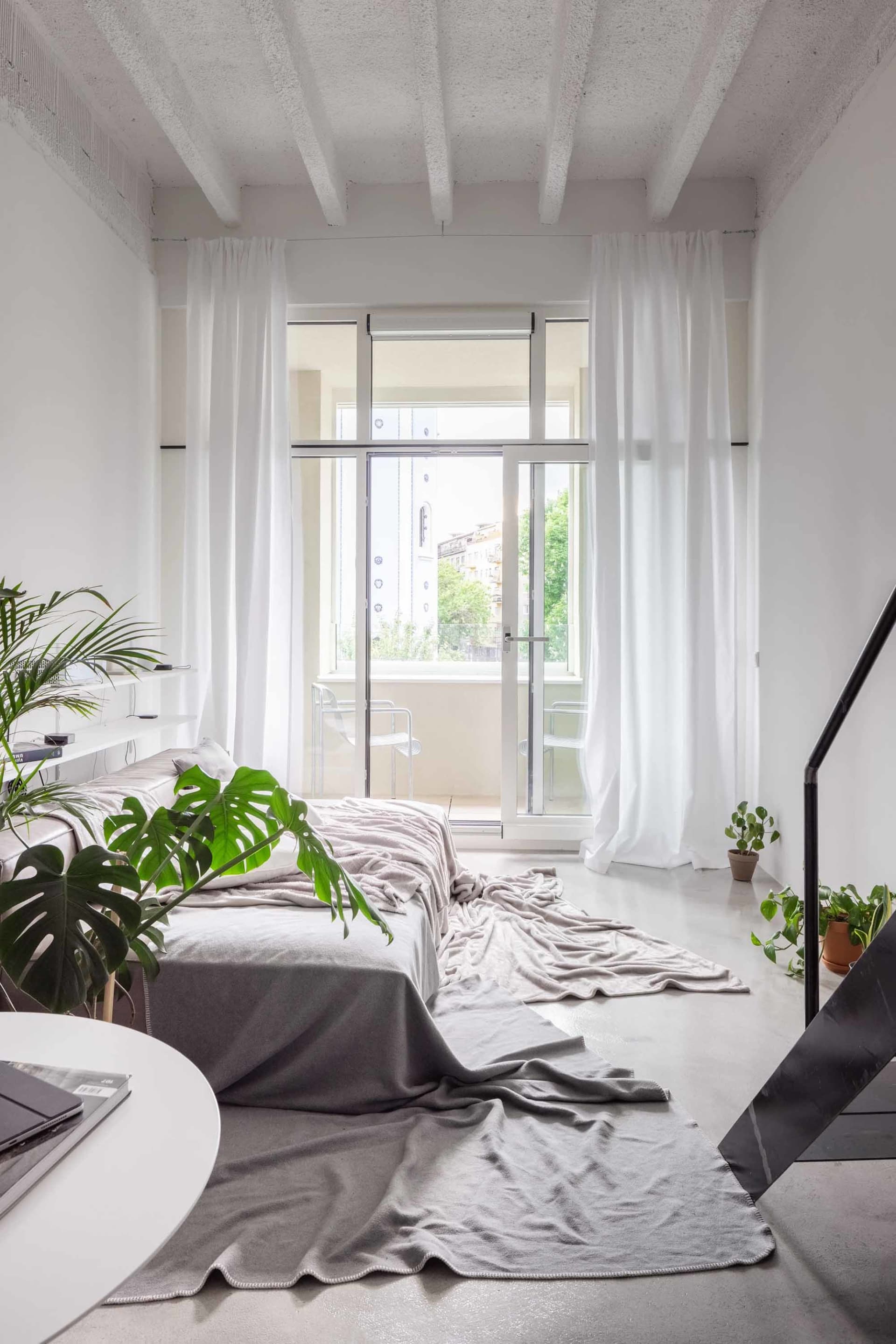 A minimalist bedroom with concrete floor and white walls.