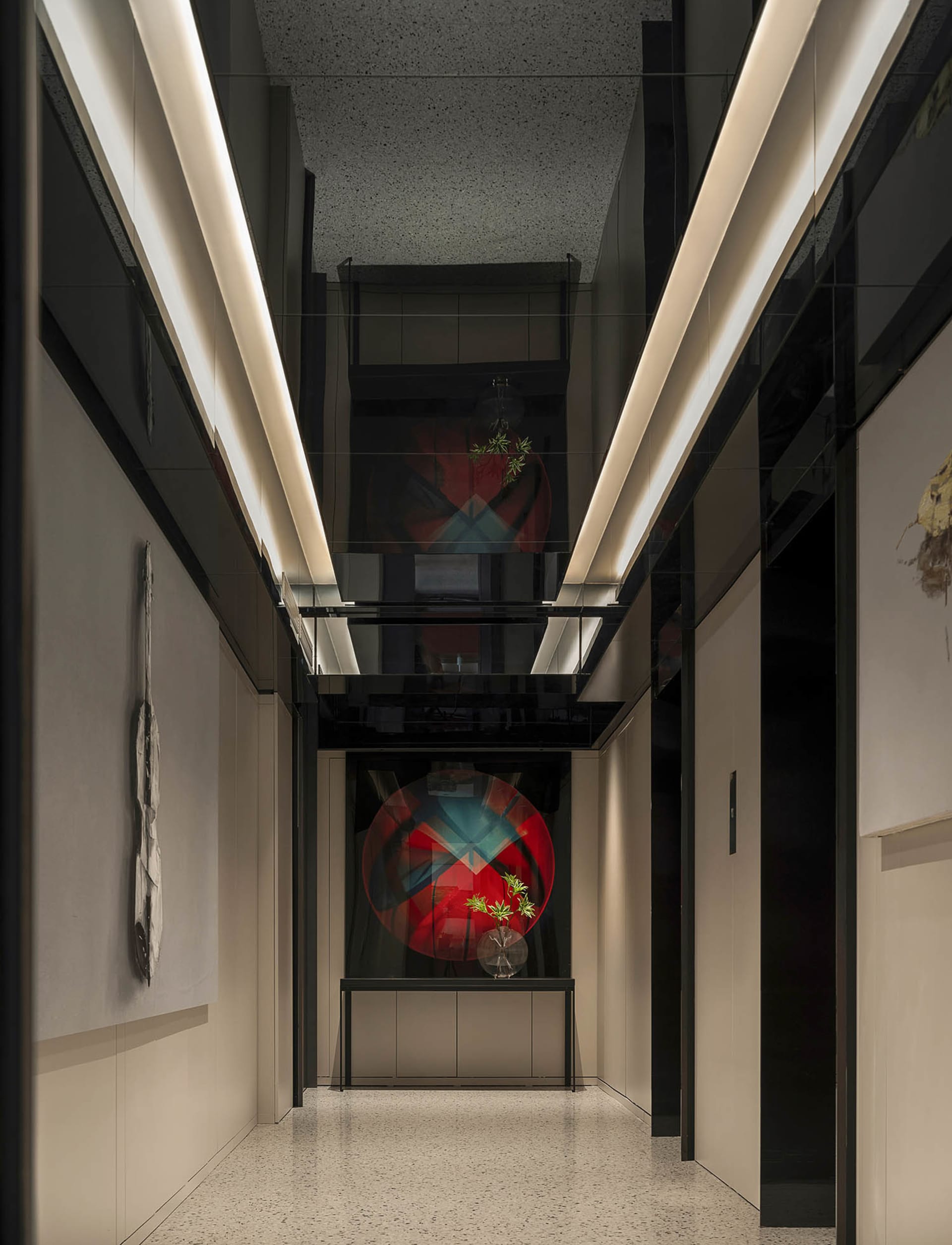 Modern interior design featuring glass walls, white panels, and a terrazzo floor in a corridor setting.