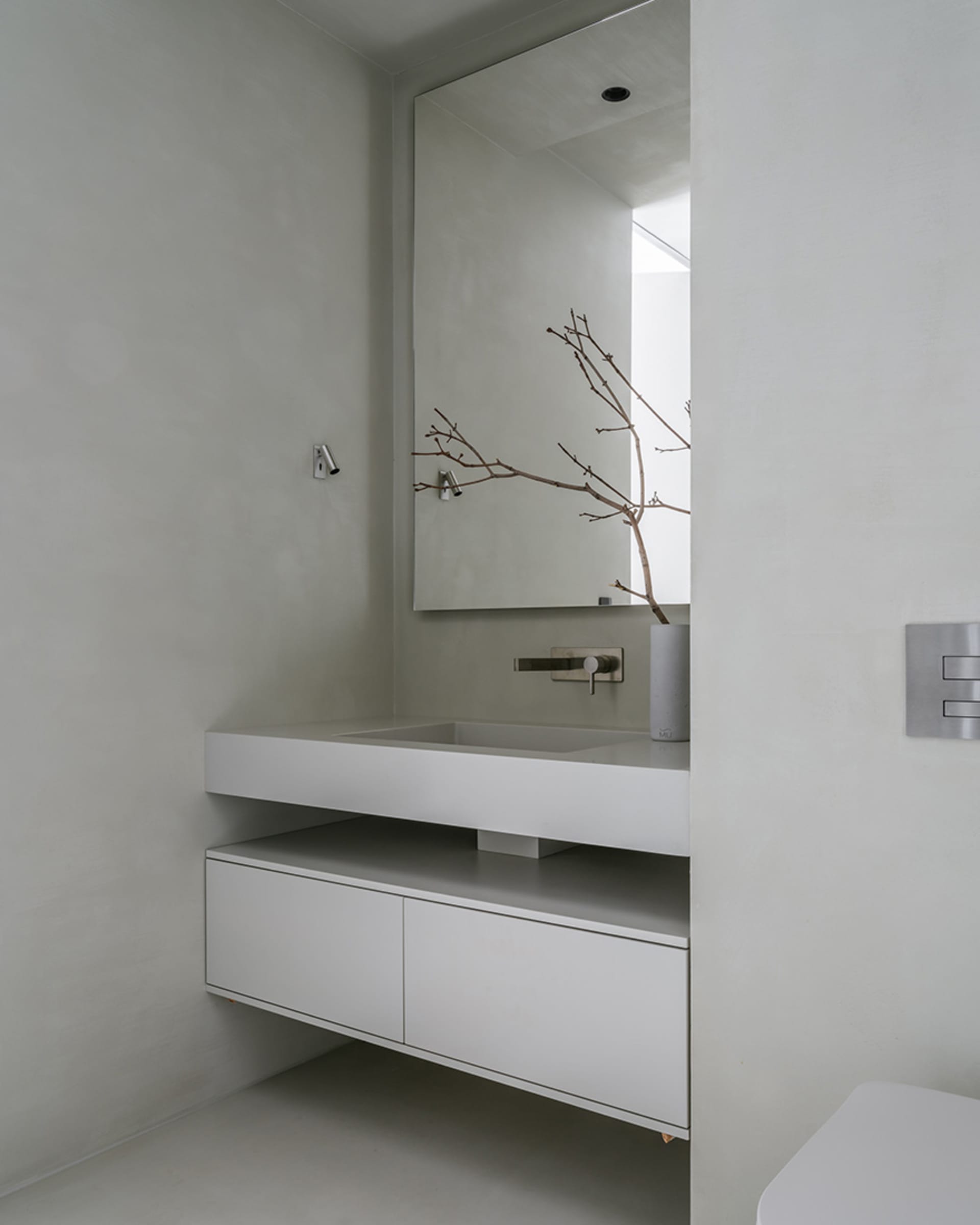 Modern minimalist bathroom with concrete sink and cabinets.