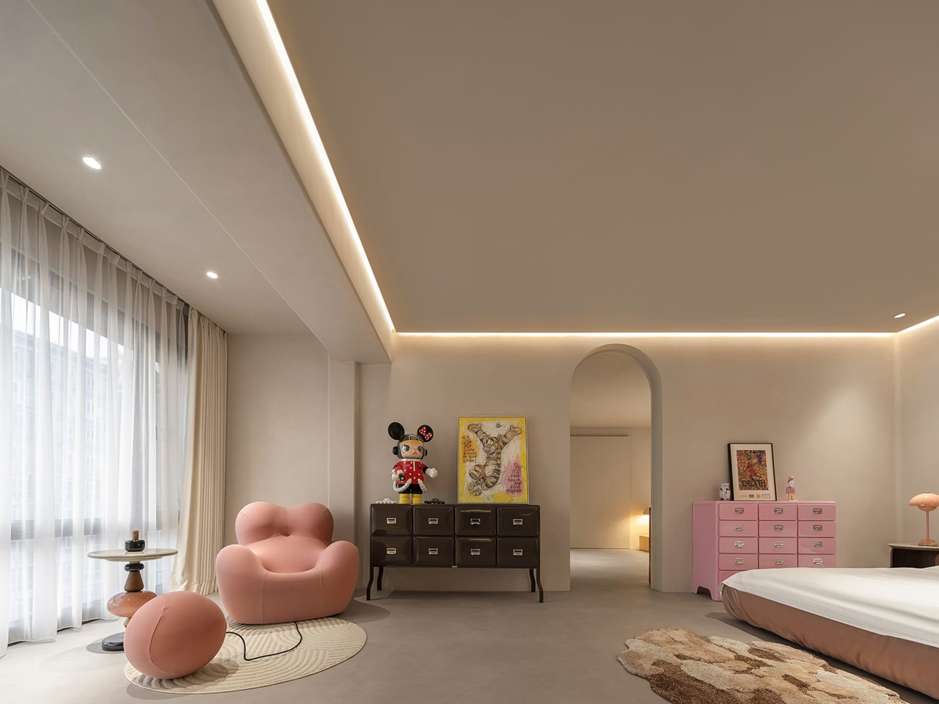 A modern bedroom with concrete walls, minimalistic furniture, and a pink chair and ottoman.