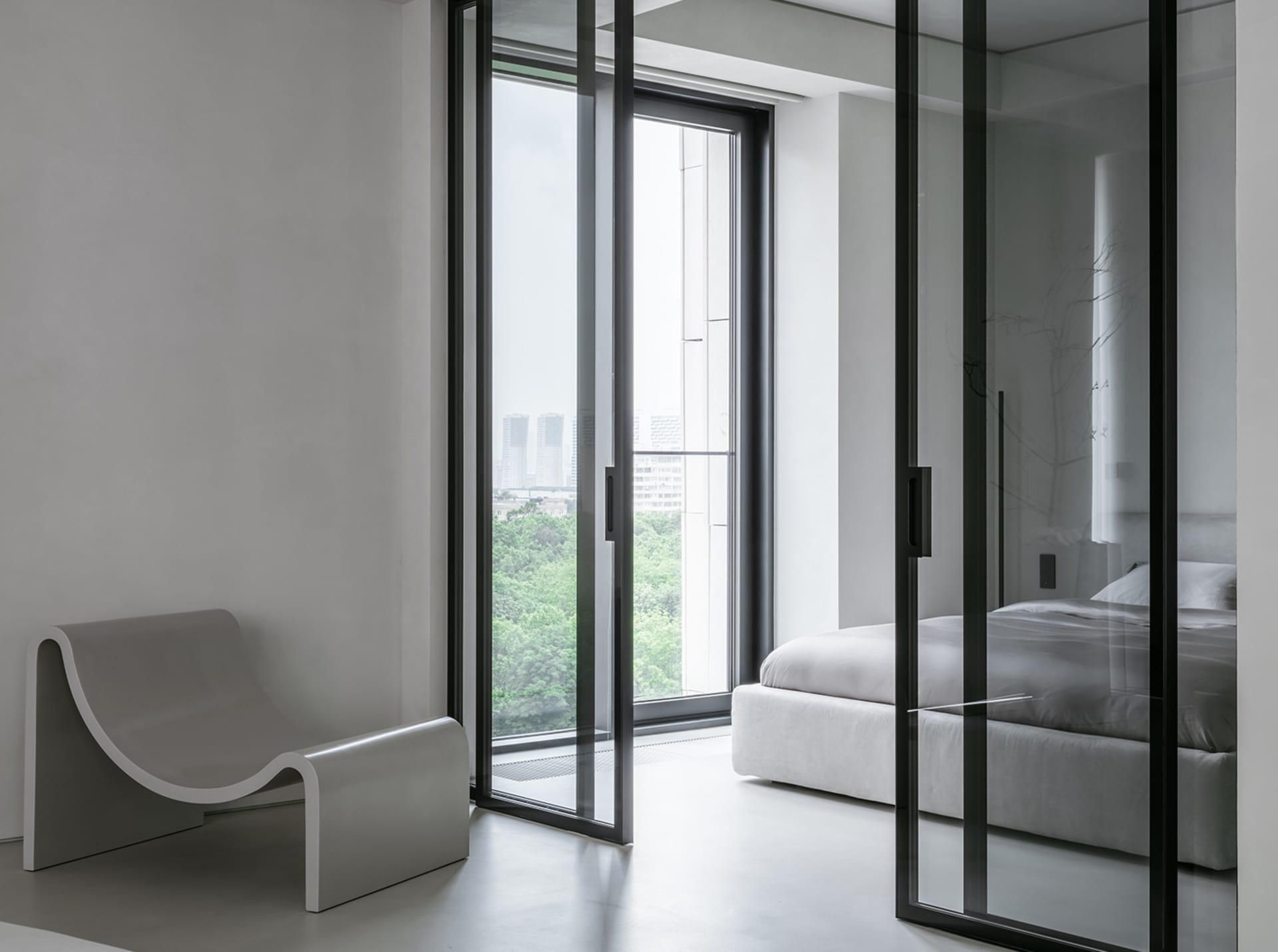 Modern minimalist bedroom featuring white furniture and glass walls.